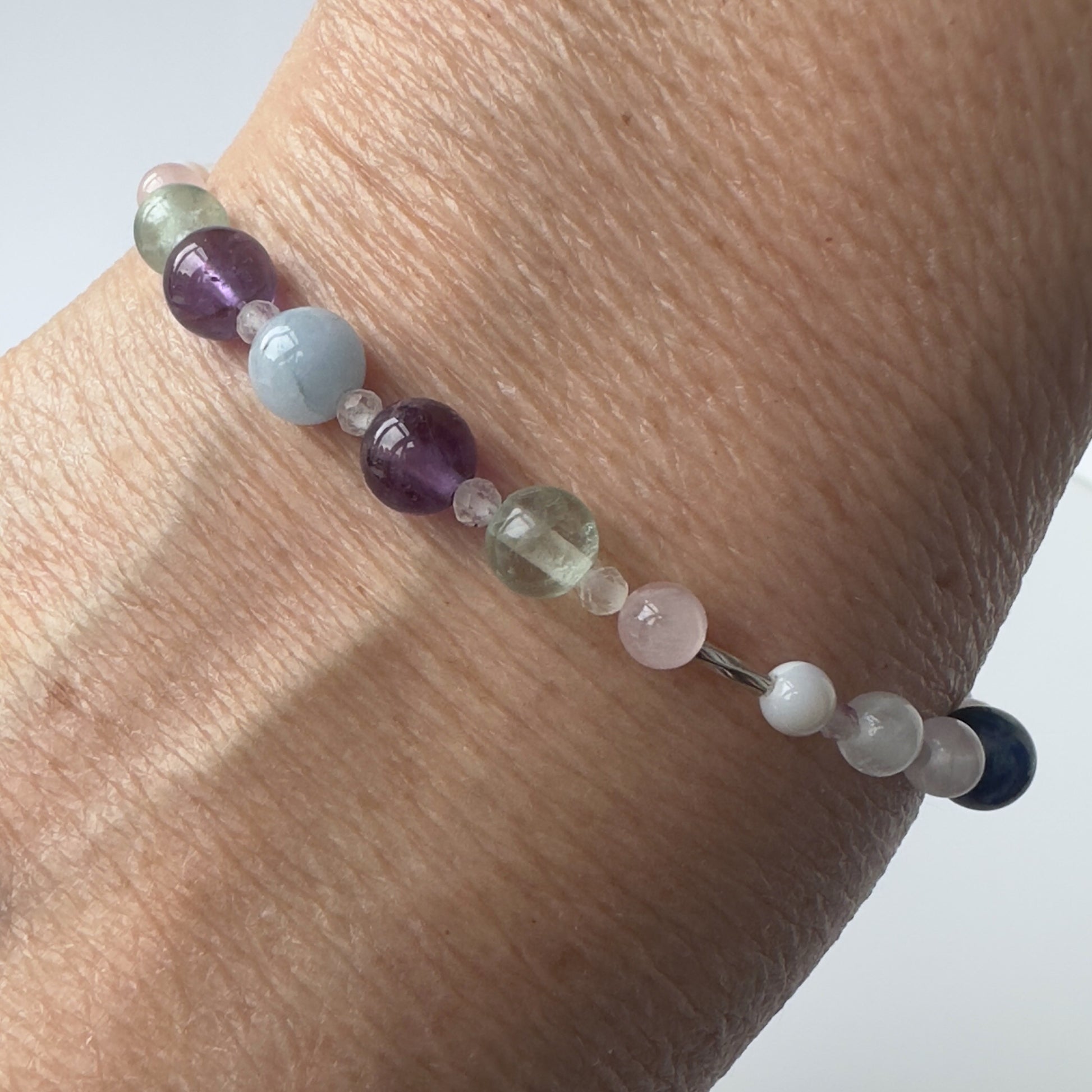 Aquarius Birthstone Healing Crystal bracelet for Calm & Anxiety Relief Close up showing Amethyst, Aquamarine, Fluorite, Moonstone and Rose Quartz on a wrist