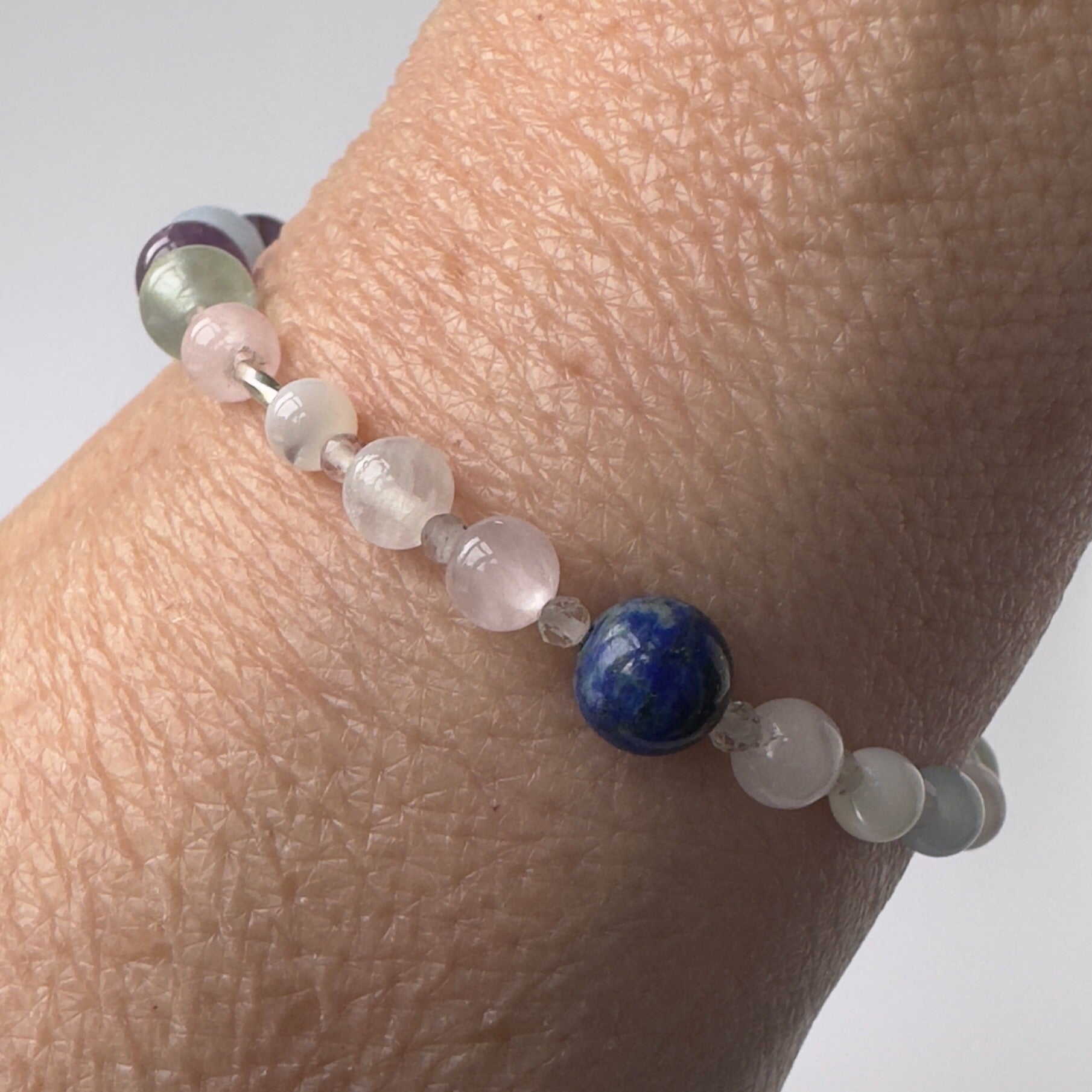 Aquarius Birthstone Healing Crystal bracelet for Calm & Anxiety Relief Close up showing Aquamarine, Fluorite, Moonstone, Azurite and Rose Quartz on a wrist