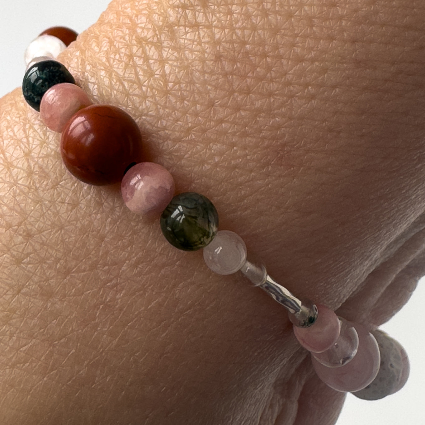 Aquarius Birthstone Healing Crystal bracelet for Love and Compassion Close-up on wrist showing Rose Quartz, Moss Agate, Red Jasper and Rhodochrosite