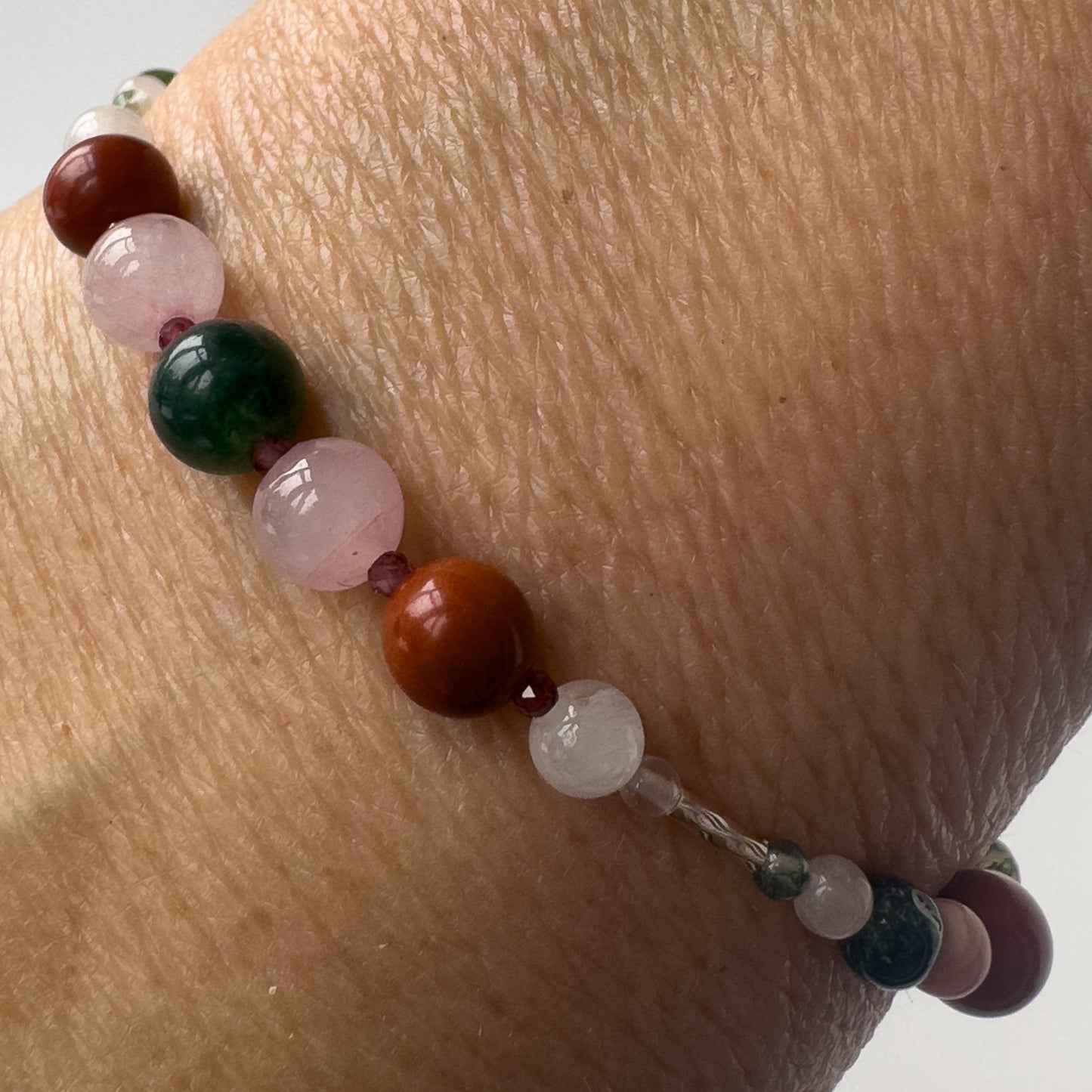 Aquarius Birthstone Healing Crystal bracelet for Love and Compassion on wrist showing Rose Quartz, Moss Agate, Garnet and Red Jasper