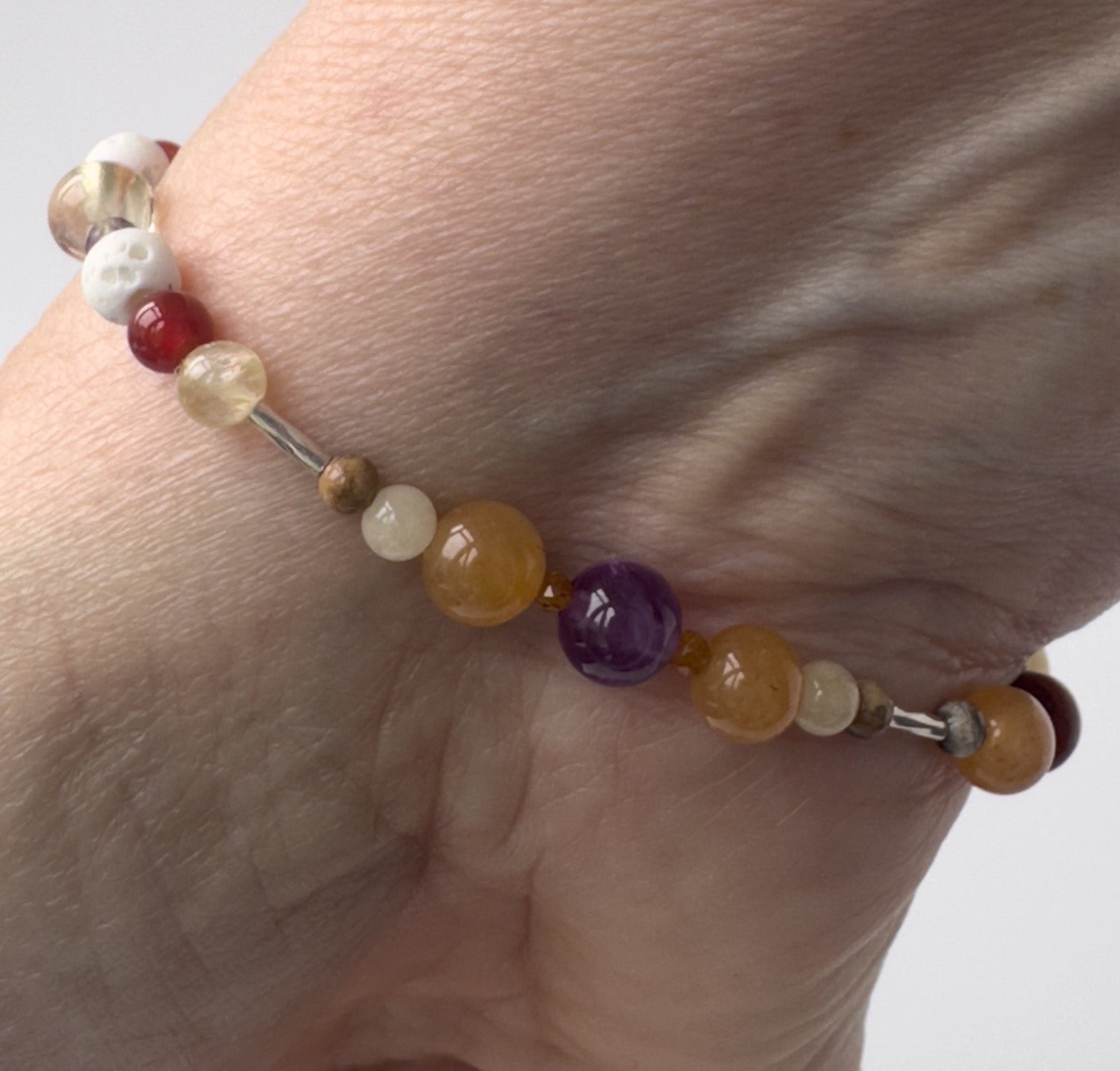Aries Birthstone Healing Crystal bracelet for Determination & Willpower Close-up on wrist showing Amethyst, Leopardskin Jasper, Aragonite, Garnet and Carnelian