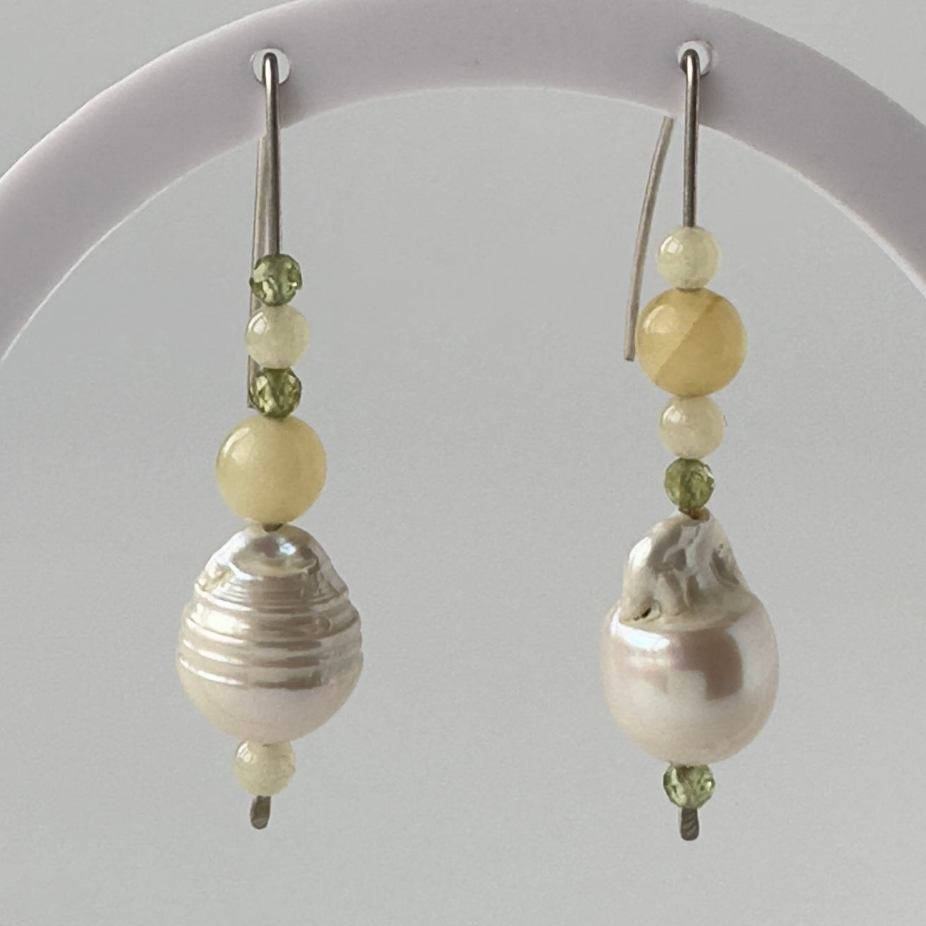 Pair of earrings with pearls and green beads on a gray background