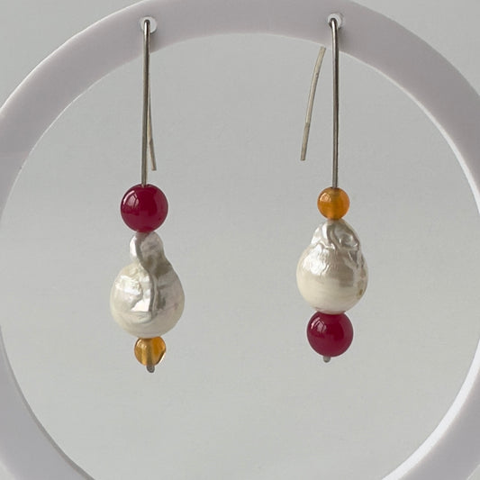 Pair of earrings with pearls and red and orange beads on a white background