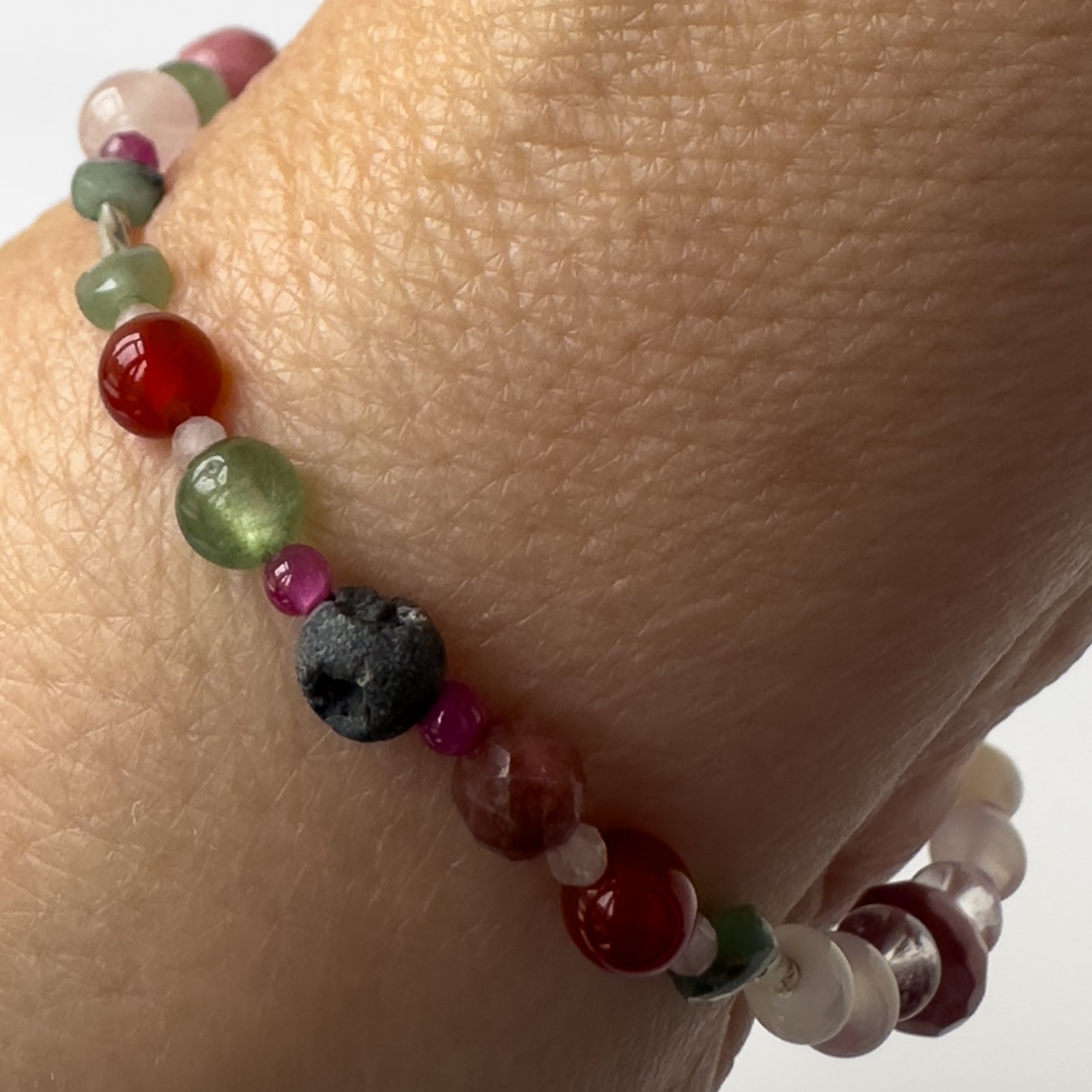 Cancer Birthstone Healing Crystal bracelet for Grief & Loss support on wrist showing Ruby, Rhodonite, Carnelian, Chalcedony, Emerald and Lava Stone