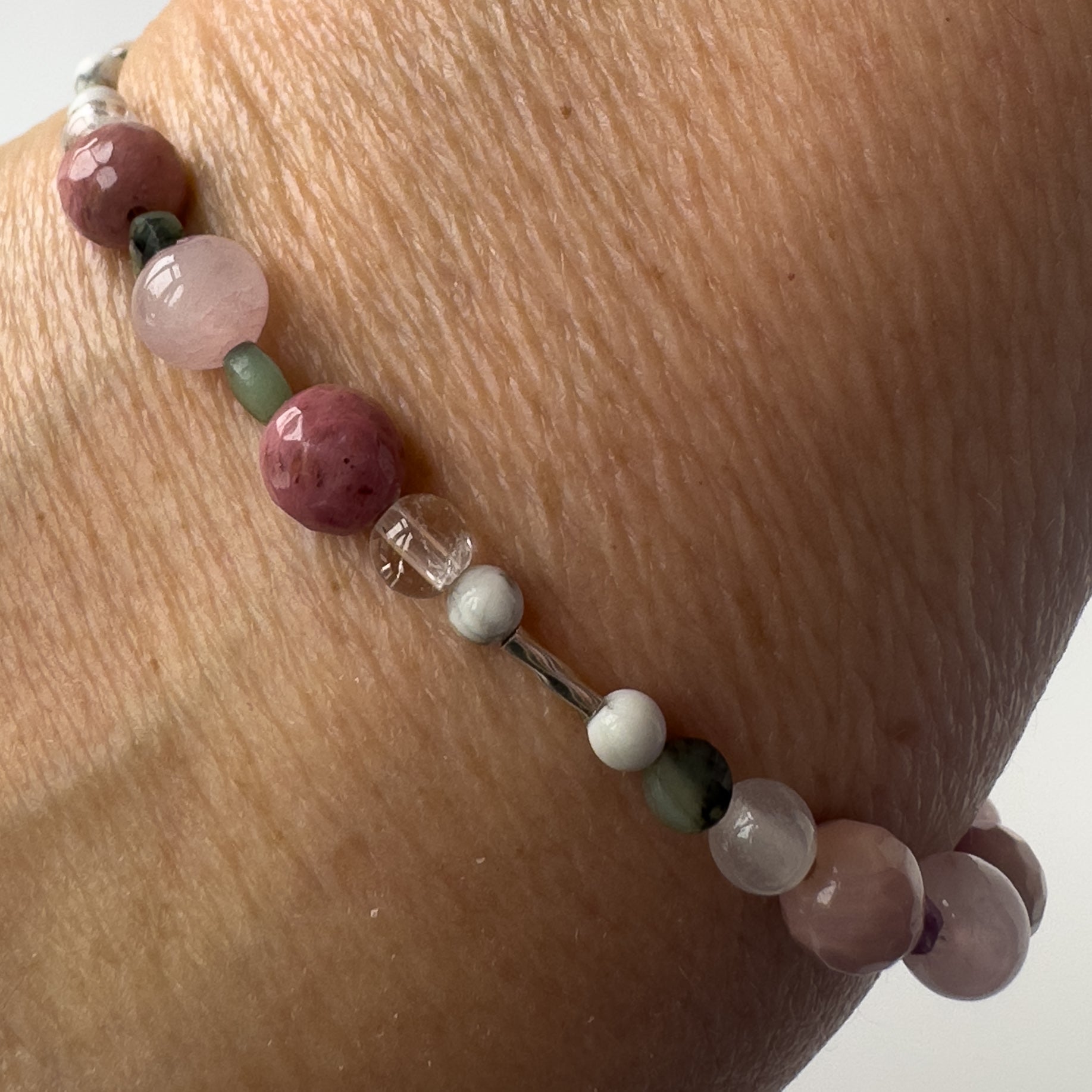 Cancer Healing Crystal bracelet for Love on wrist showing Rose Quartz, Emerald, Howlite, Rhodonite and Clear Quartz