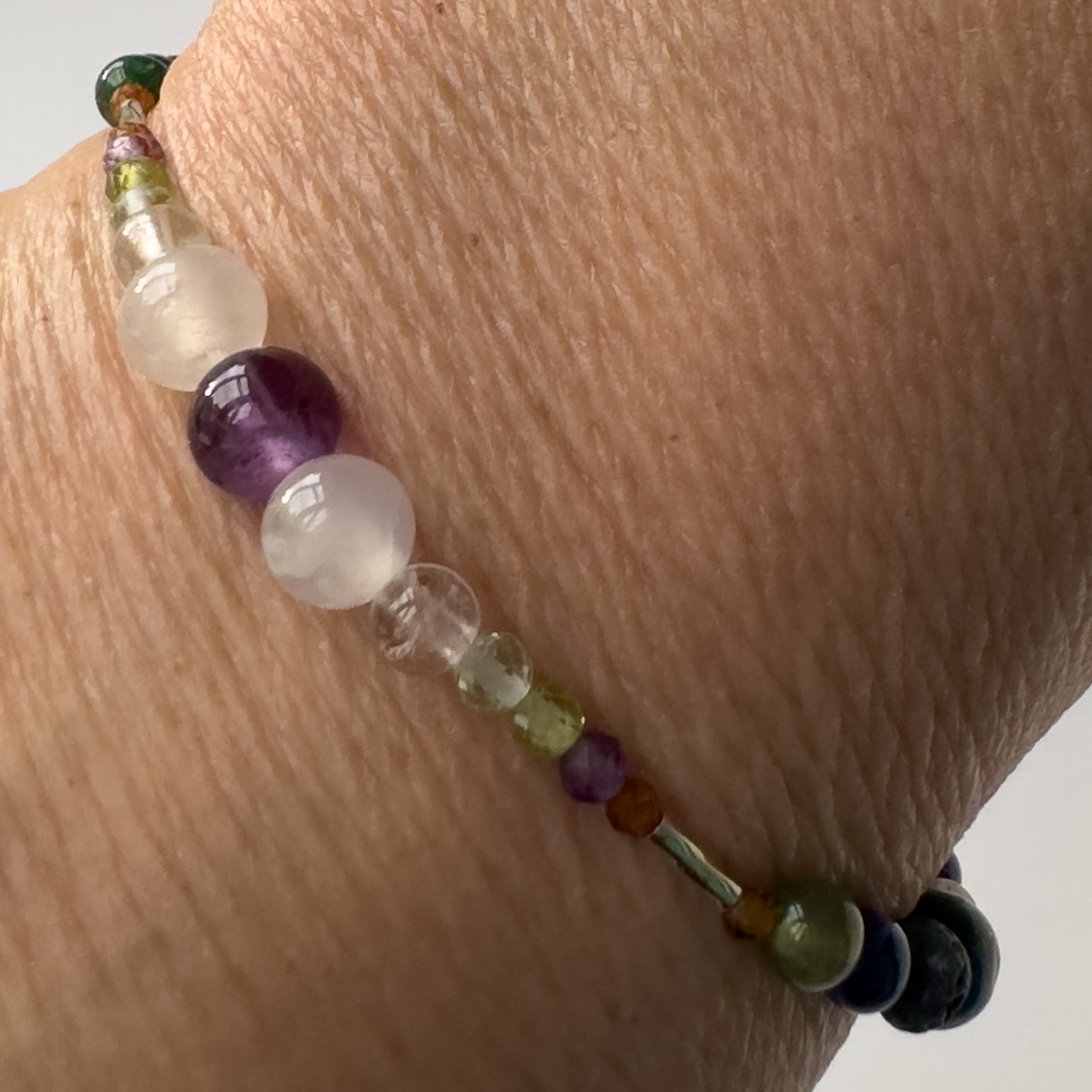 Capricorn Handmade Healing Crystal bracelet for Stress on wrist showing Garnet, Peridot, Amethyst, Fluorite, Selenite and Clear Quartz