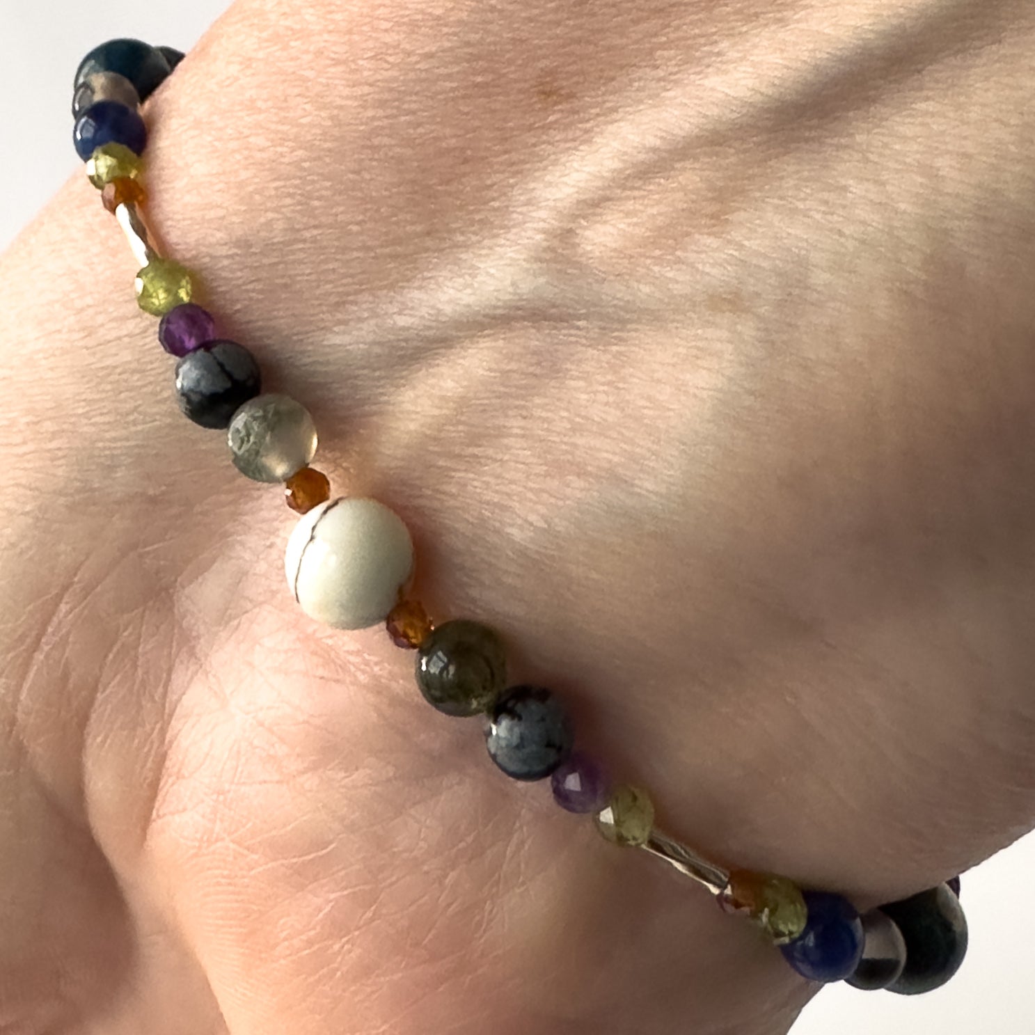 Capricorn birthstone Healing Crystal bracelet for Calm & Stress relief on wrist showing Garnet, Moss Agate, Peridot, Snowflake Obsidian, Amethyst and Magnesite