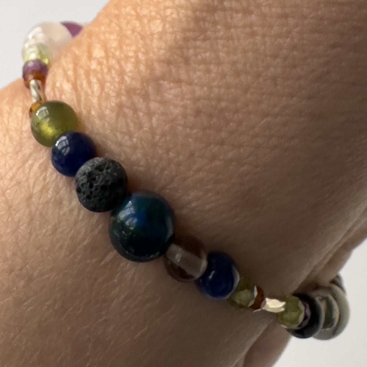 Capricorn birthstone Healing Crystal bracelet for Stress on wrist showing Garnet, Moss Agate, Peridot, Snowflake Obsidian, smoky Quartz, Azurite, Sodalite and Lava Stone
