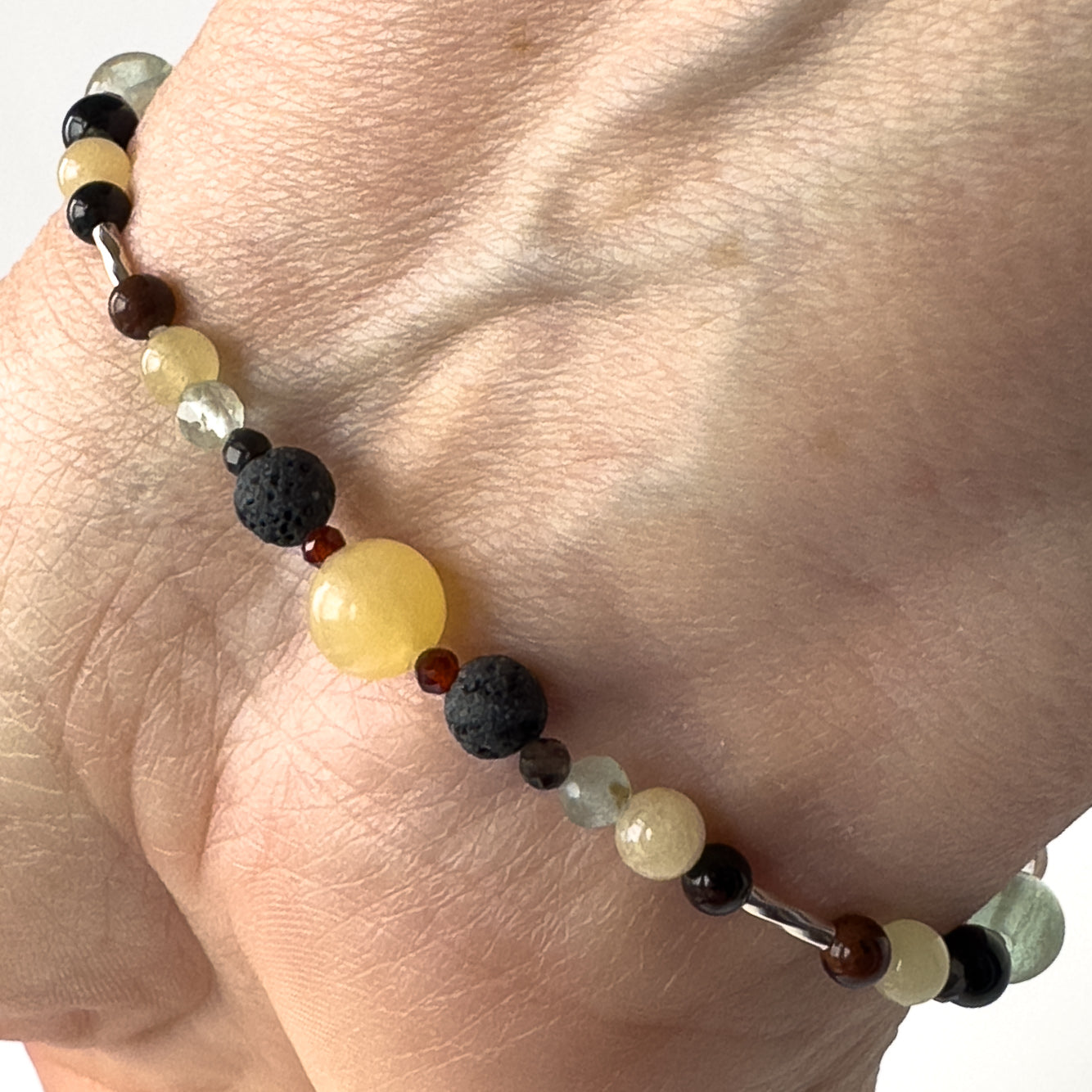 Capricorn Birthstone Healing Crystal bracelet for Confidence on wrist showing Garnet, Mahogany Obsidian, Onyx, Fluorite and Aragonite