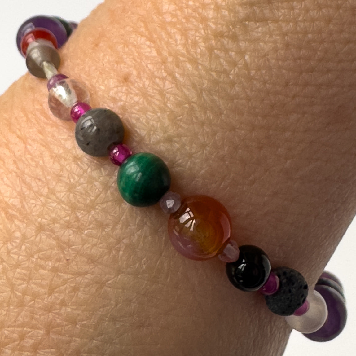 Capricorn Birthstone Healing Crystal bracelet for Grief & Loss support on wrist showing Onyx, Malachite, Labradorite, Ruby, Carnelian, Selenite, Clear Quartz and Lava Stone