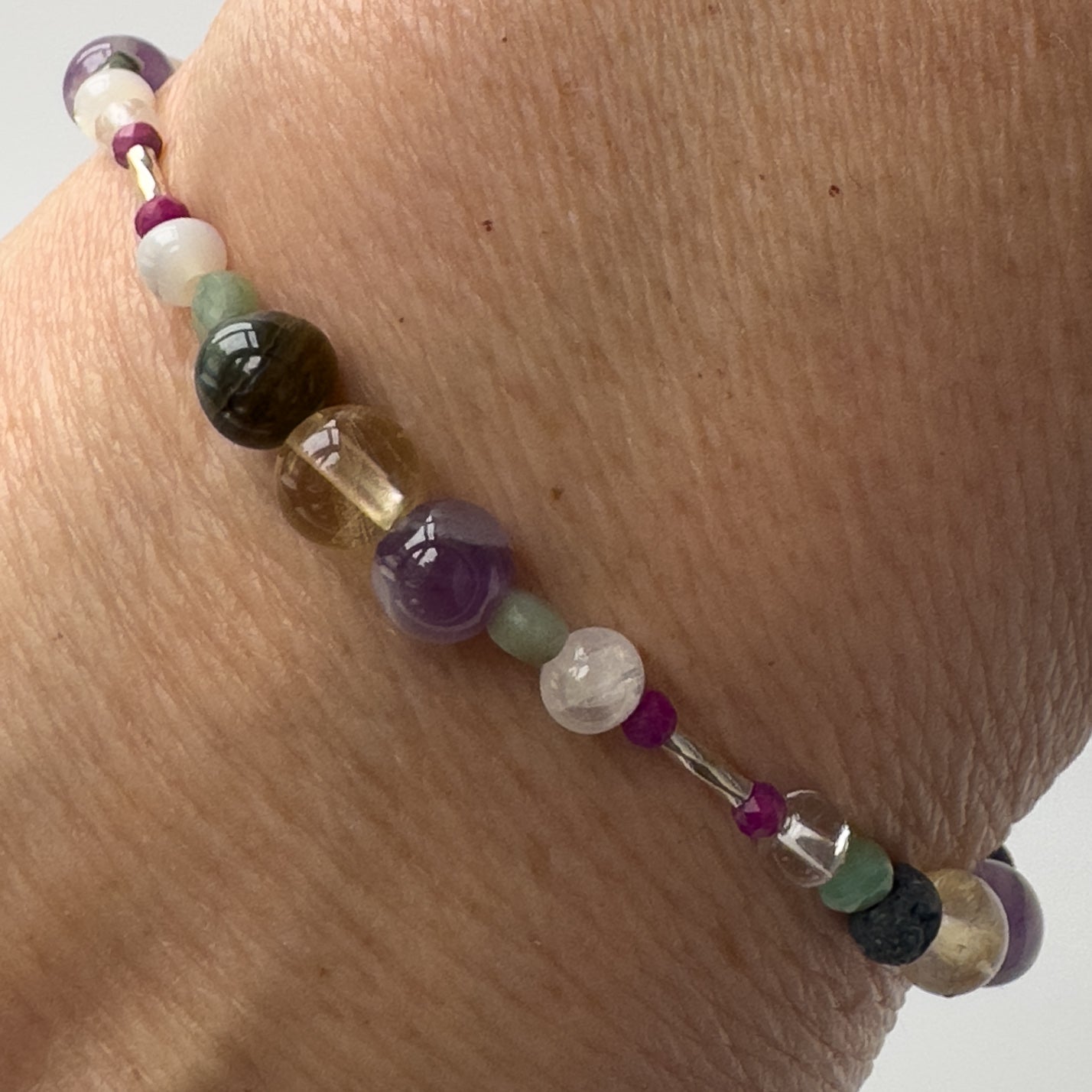 Gemini Healing Crystal bracelet for Grief & Loss on wrist showing Emerald, Moonstone, Blue Tiger’s Eye, Citrine, Amethyst, Sugilite