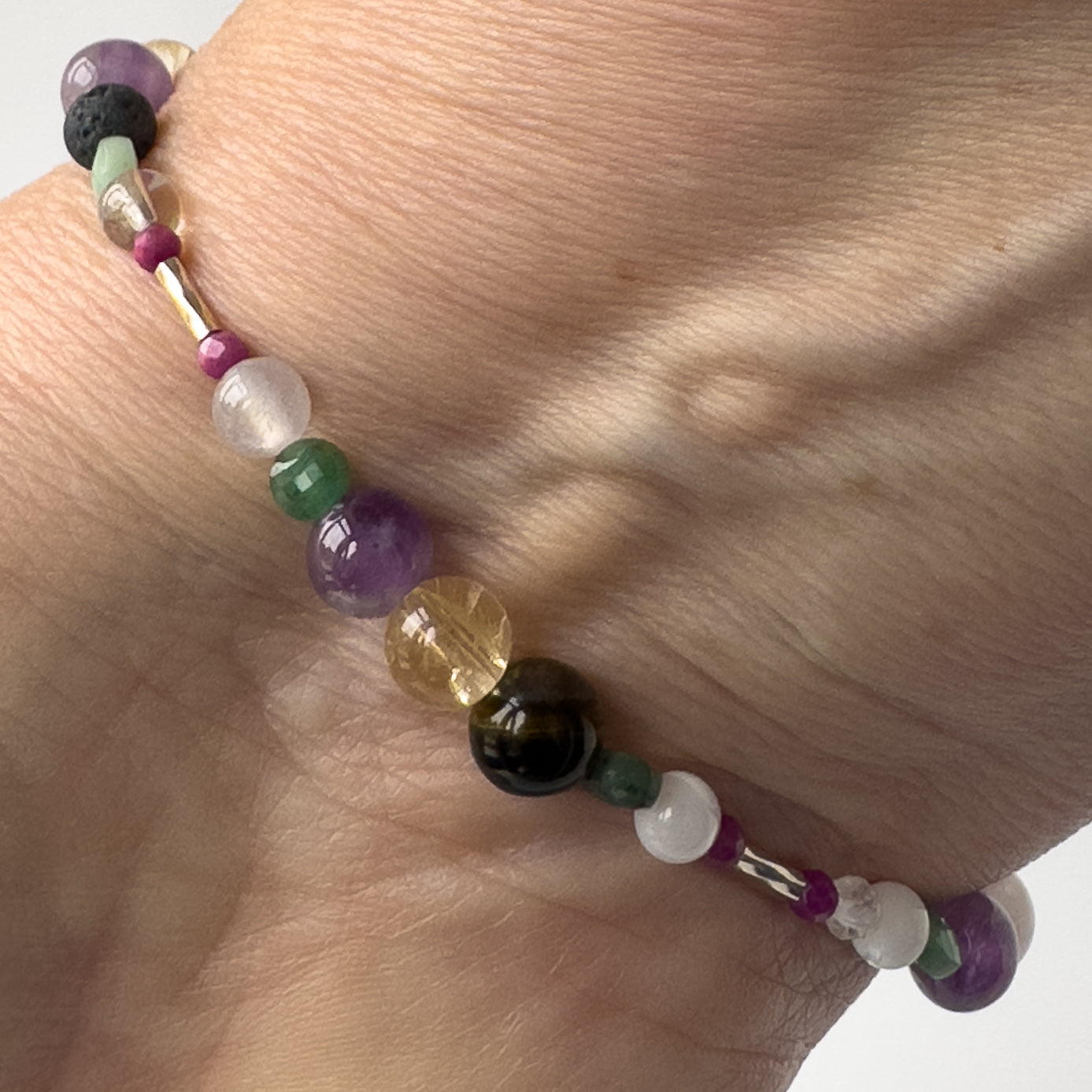 Gemini Birthstone Healing Crystal bracelet for Grief & Loss support on wrist showing Emerald, Moonstone, Blue Tiger’s Eye, Citrine, Amethyst, Sugilite and Selenite