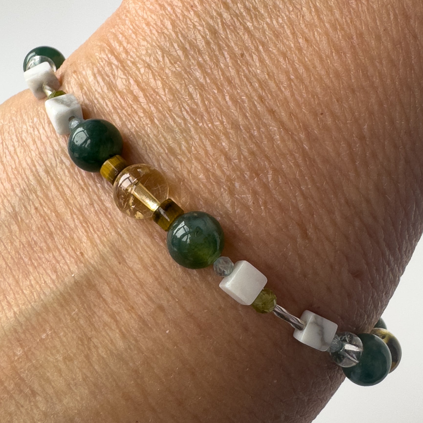 Gemini Healing Crystal bracelet for Love on wrist showing Citrine, Peridot, Moss Agate, Howlite, Tiger’s Eye and Topaz