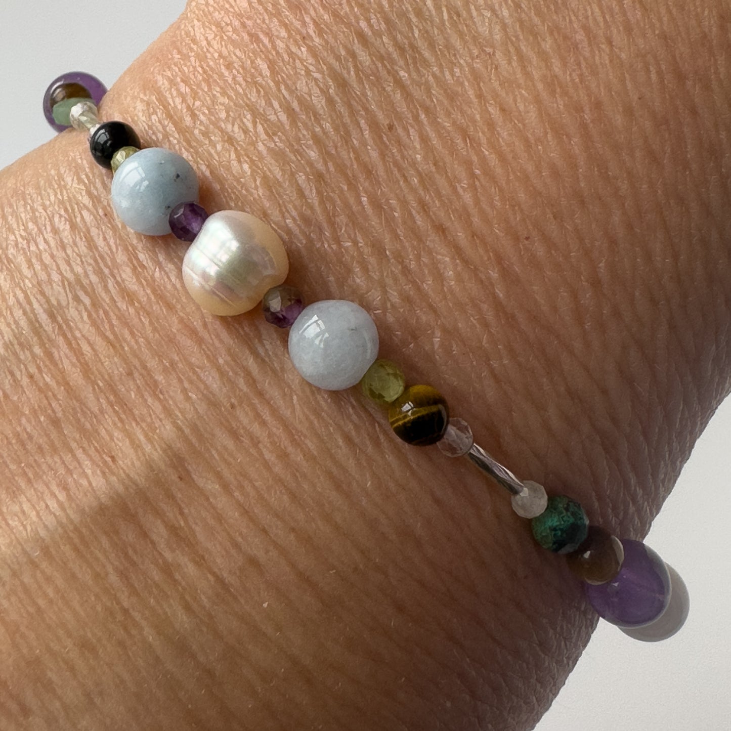 Gemini Healing Crystal bracelet for Stress on wrist showing Yellow Tiger’s Eye, Aquamarine, Peridot, Pearl and Clear Quartz