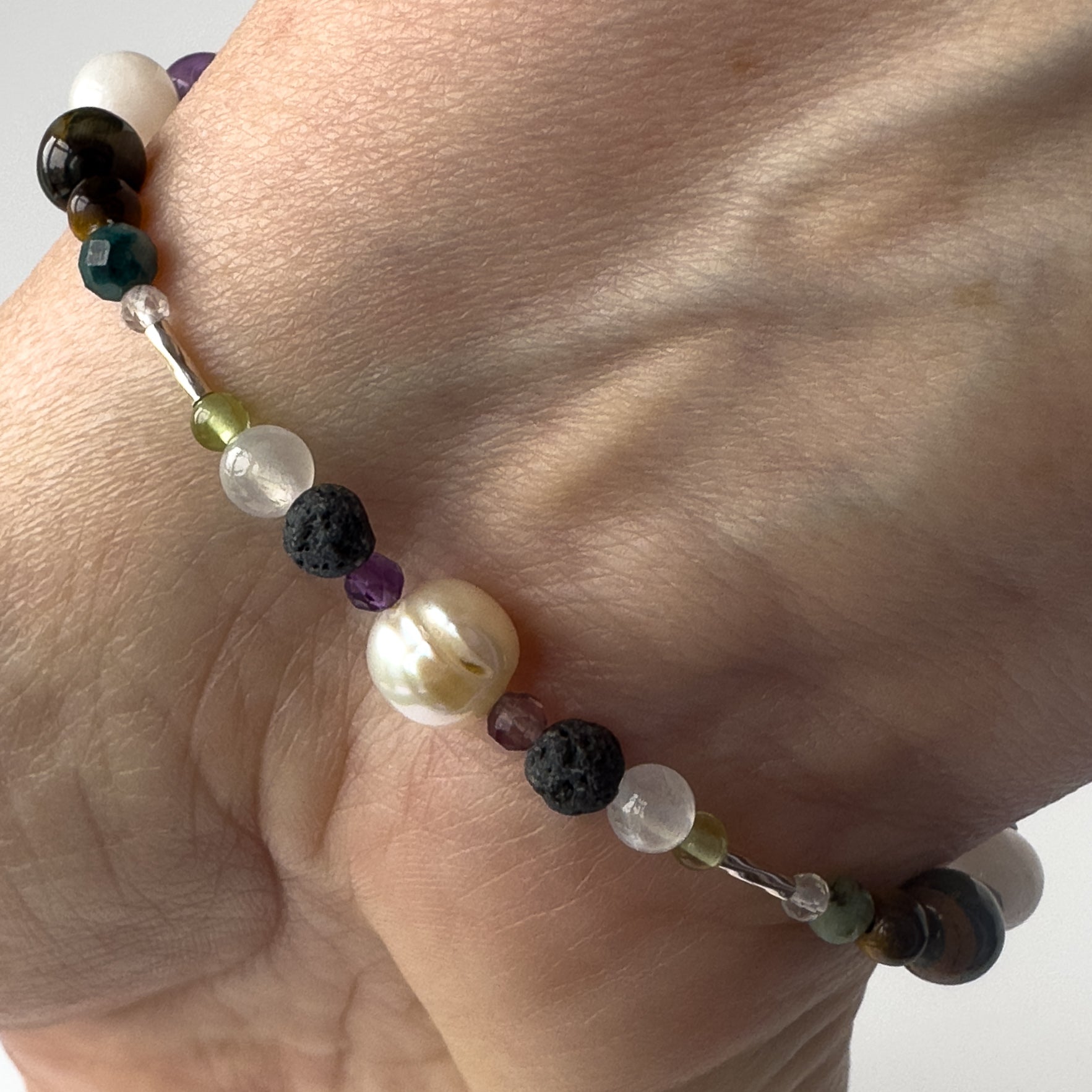 Gemini birthstone Healing Crystal bracelet for Calm & Stress relief on wrist showing Peridot, Pearl, Amethyst, Selenite and Lava Stone