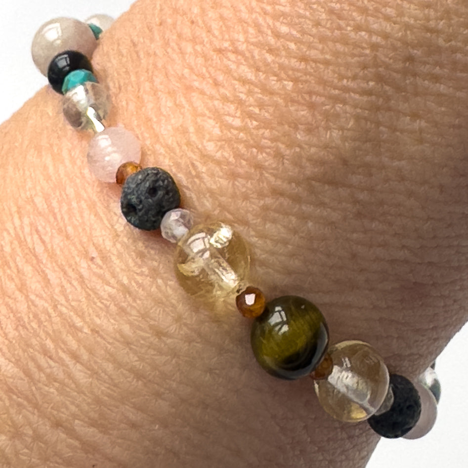Leo Birthstone Healing Crystal bracelet for Calm & Anxiety Relief on wrist showing Blue Tiger’s Eye, Rose Quartz, Citrine, Garnet, Kunzite, Turquoise and Lava Stone