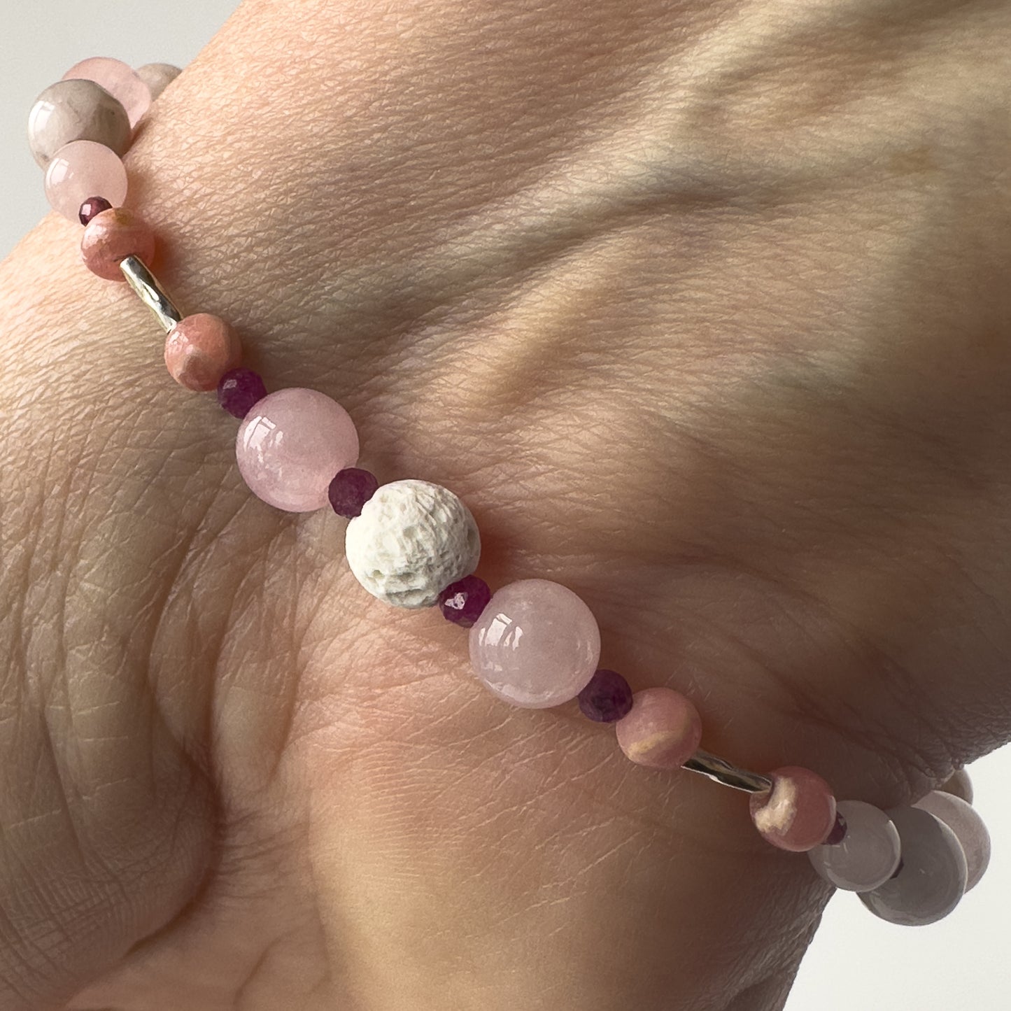 Leo birthstone Healing Crystal bracelet for Love and Compassion on wrist showing Rose Quartz, Garnet, Rhodochrosite, Ruby and Lava Stone