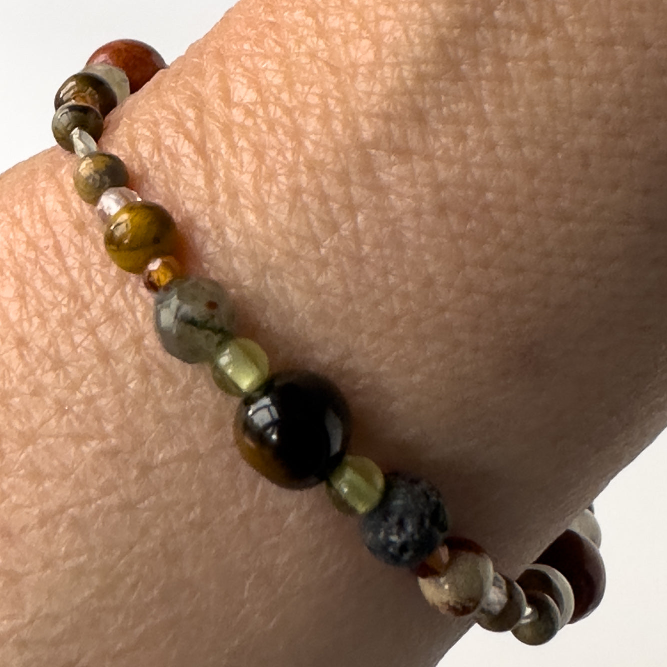 Leo Birthstone Healing Crystal bracelet for Calm & Stress relief on wrist showing Blue Tiger’s Eye, Yellow Tiger’s Eye, Peridot, Garnet, Bloodstone and Lava Stone