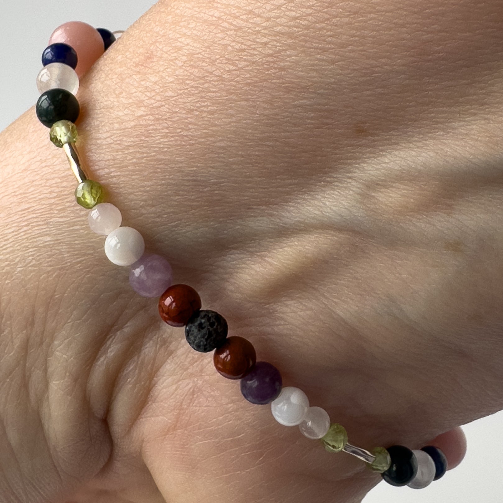 Libra Birthstone Healing Crystal bracelet for Calm & Stress relief on wrist showing Peridot, Rose Quartz, Lepidolite, Moonstone, Jasper, and Lava Stone