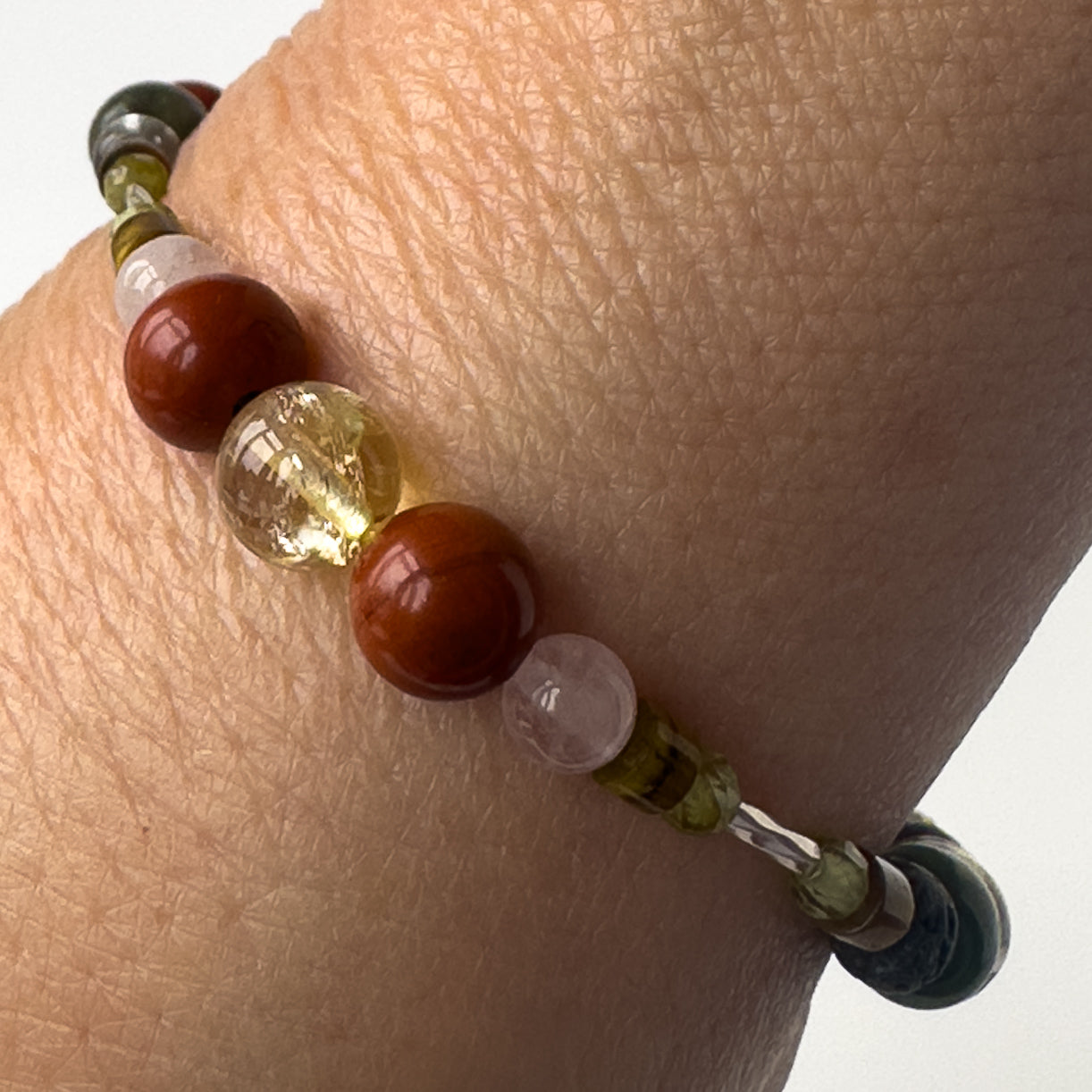 Pisces Birthstone Healing Crystal bracelet for Love and Compassion on wrist showing Rose Quartz, Citrine, Peridot, Red Jasper and Tiger’s Eye