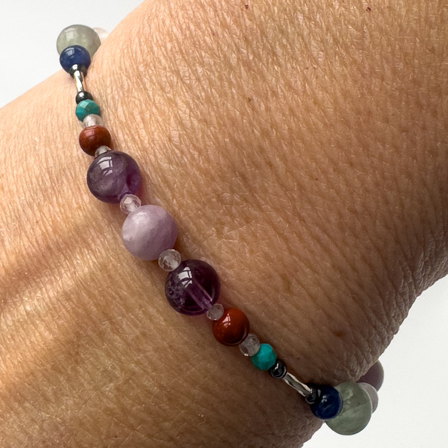 Pisces Healing Crystal bracelet for Willpower on wrist showing Amethyst, Lepidolite, Hematite, Turquoise, Red Jasper, Rainbow Fluorite and Clear Quartz