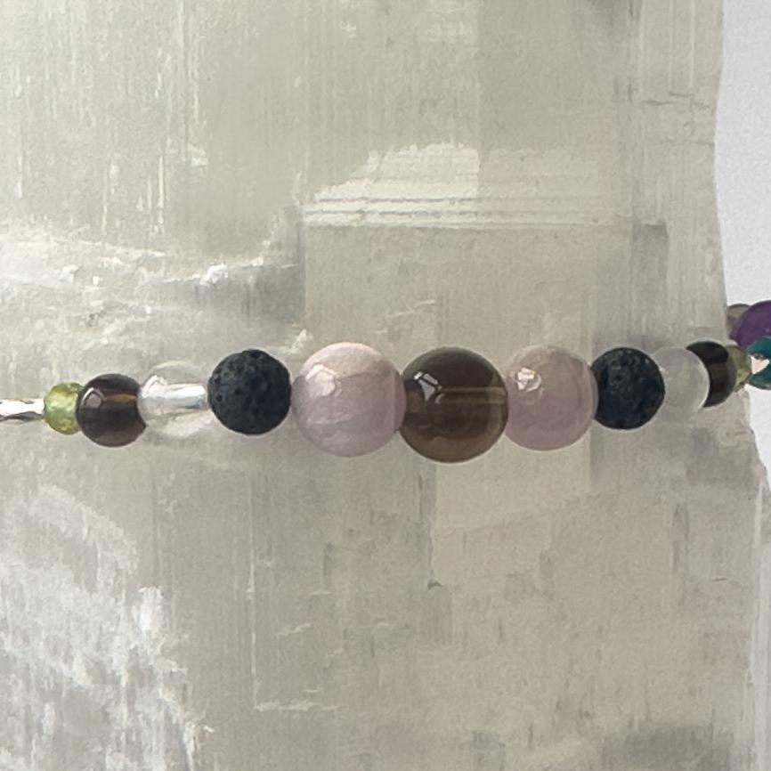 Scorpio Birthstone Healing Crystal bracelet for Calm & Anxiety Relief showing Smoky Quartz, Peridot, Kunzite, Selenite, Clear Quartz and Lava Stone