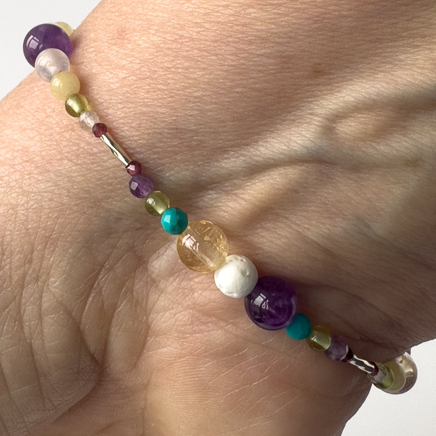 Scorpio Birthstone Healing Crystal bracelet for Determination & Willpower on wrist showing Citrine, Lava Stone, Amethyst, Turquoise, Peridot & garnet