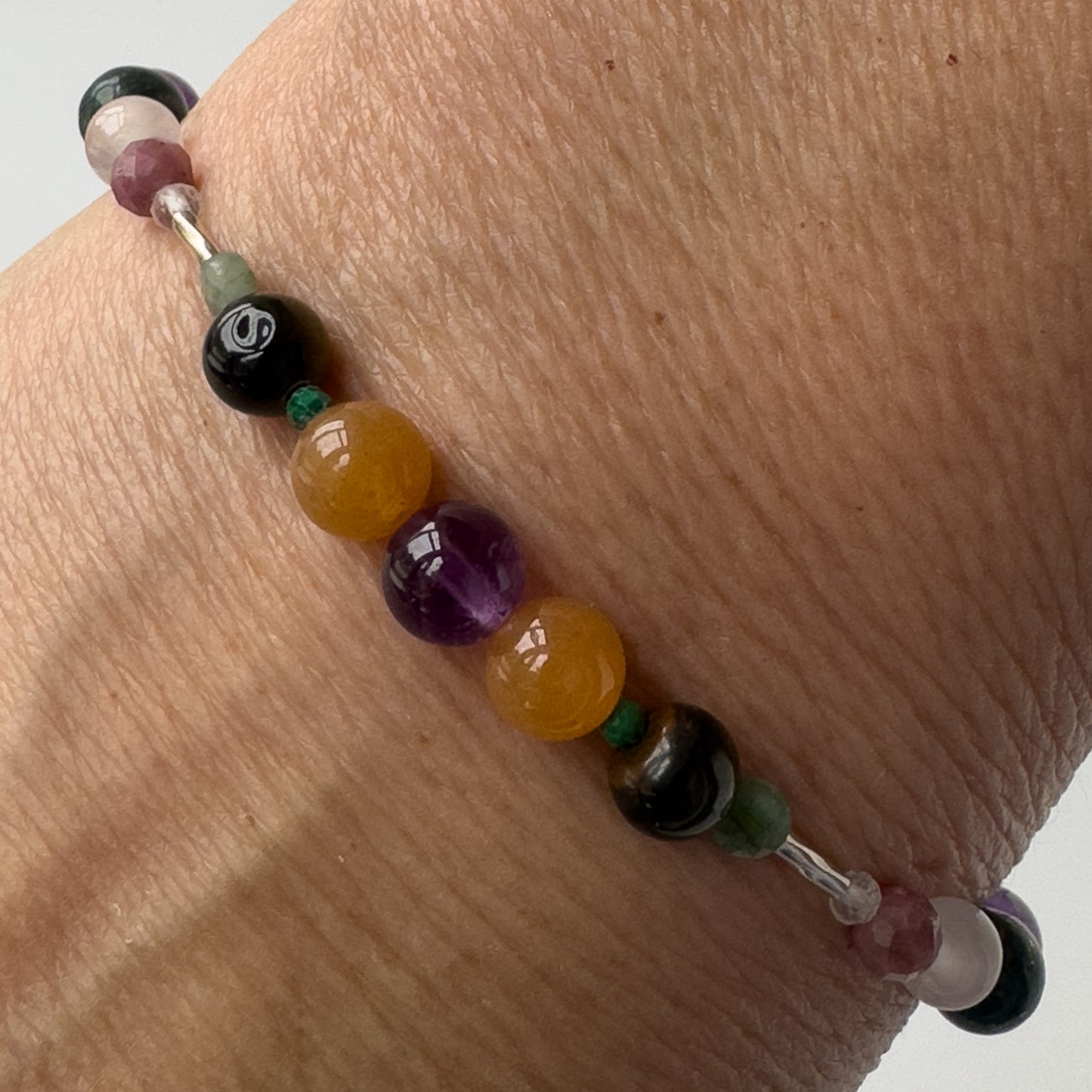 Taurus Crystal Healing bracelet for Grief & Loss on wrist showing Emerald, Amethyst, Malachite, Carnelian and Blue Tiger’s Eye