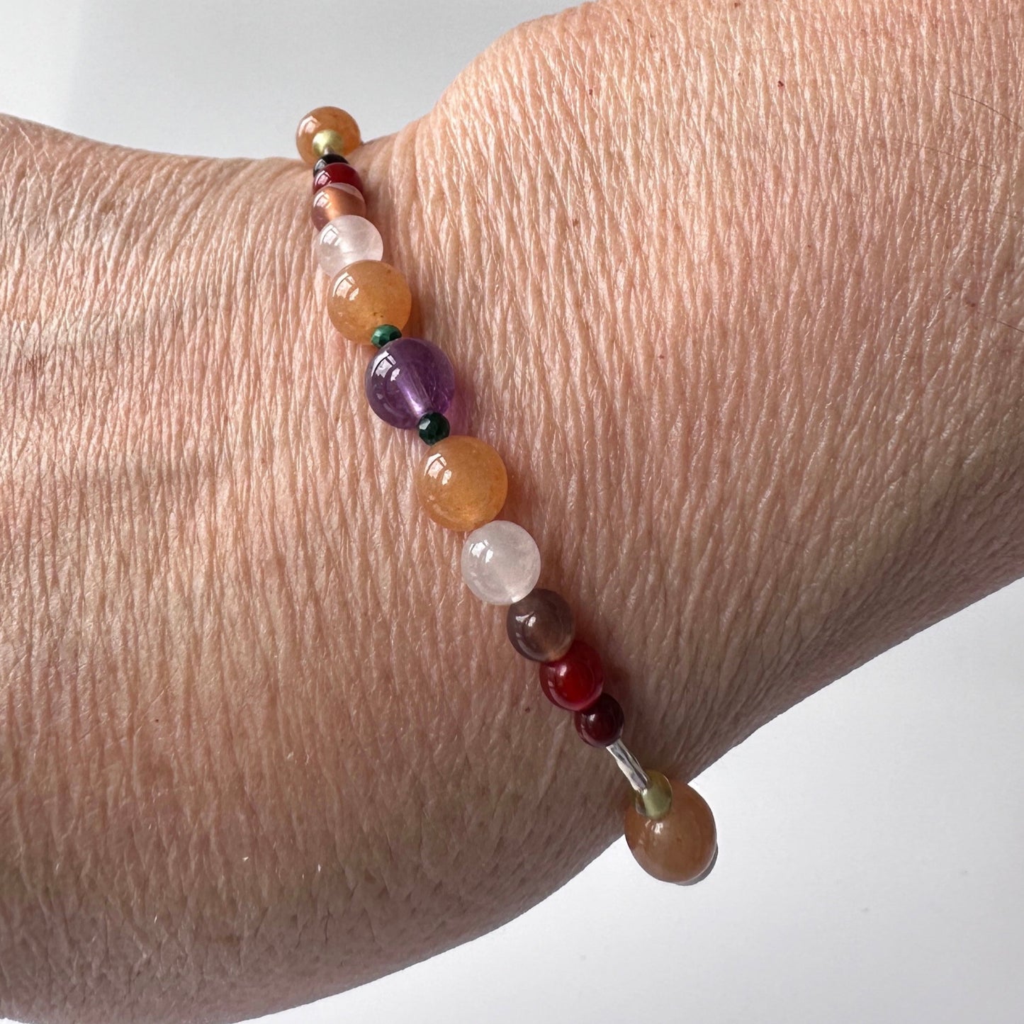 Taurus Handmade Healing Crystal bracelet for Willpower on wrist showing Amethyst, Malachite, Botswana Agate, Carnelian, Red Tiger’s Eye and  Selenite