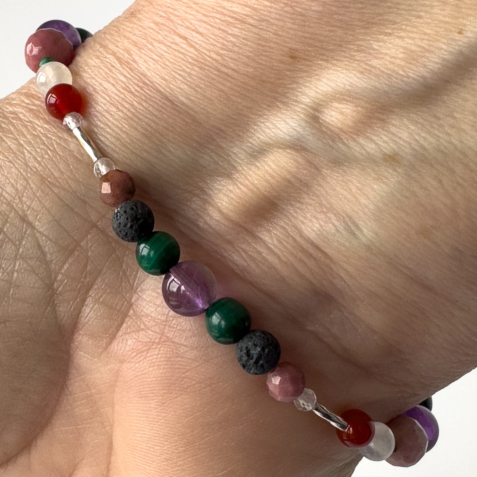 Taurus Birthstone Healing Crystal bracelet for Grief & Loss support on wrist showing Amethyst, Malachite, Rhodonite, Clear Quartz and Lava Stone