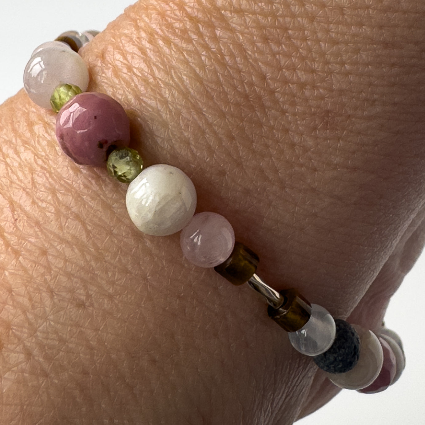 Taurus Birthstone Healing Crystal bracelet for Love and Compassion on wrist showing Rose Quartz, Peridot, Kunzite, Rhodonite and Tiger’s Eye