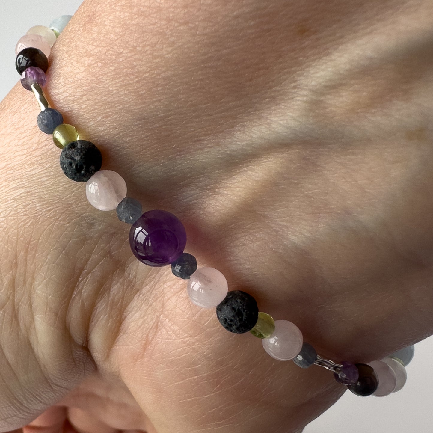 Taurus Birthstone Healing Crystal bracelet for Calm & Stress relief on wrist showing Amethyst, Peridot, Rose Quartz, Sapphire and Lava Stone