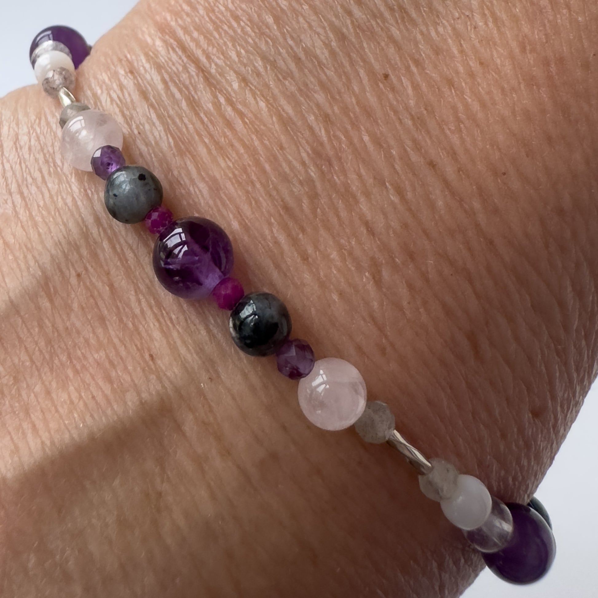 Aquarius Birthstone Healing Crystal bracelet for Grief & Loss support on wrist showing Amethyst, Sugilite, Labradorite and Rose Quartz