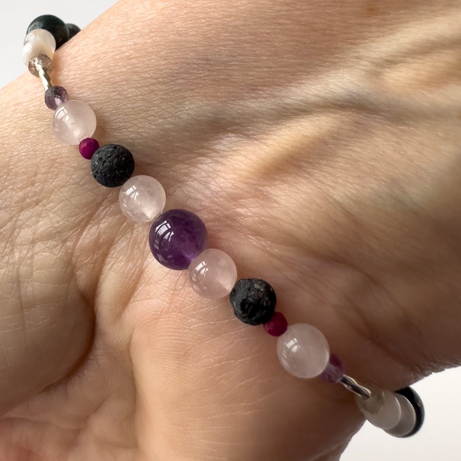 Aquarius Birthstone Healing Crystal bracelet for Grief & Loss support on wrist showing Amethyst, Sugilite, Rose Quartz, Selenite and Lava Stone