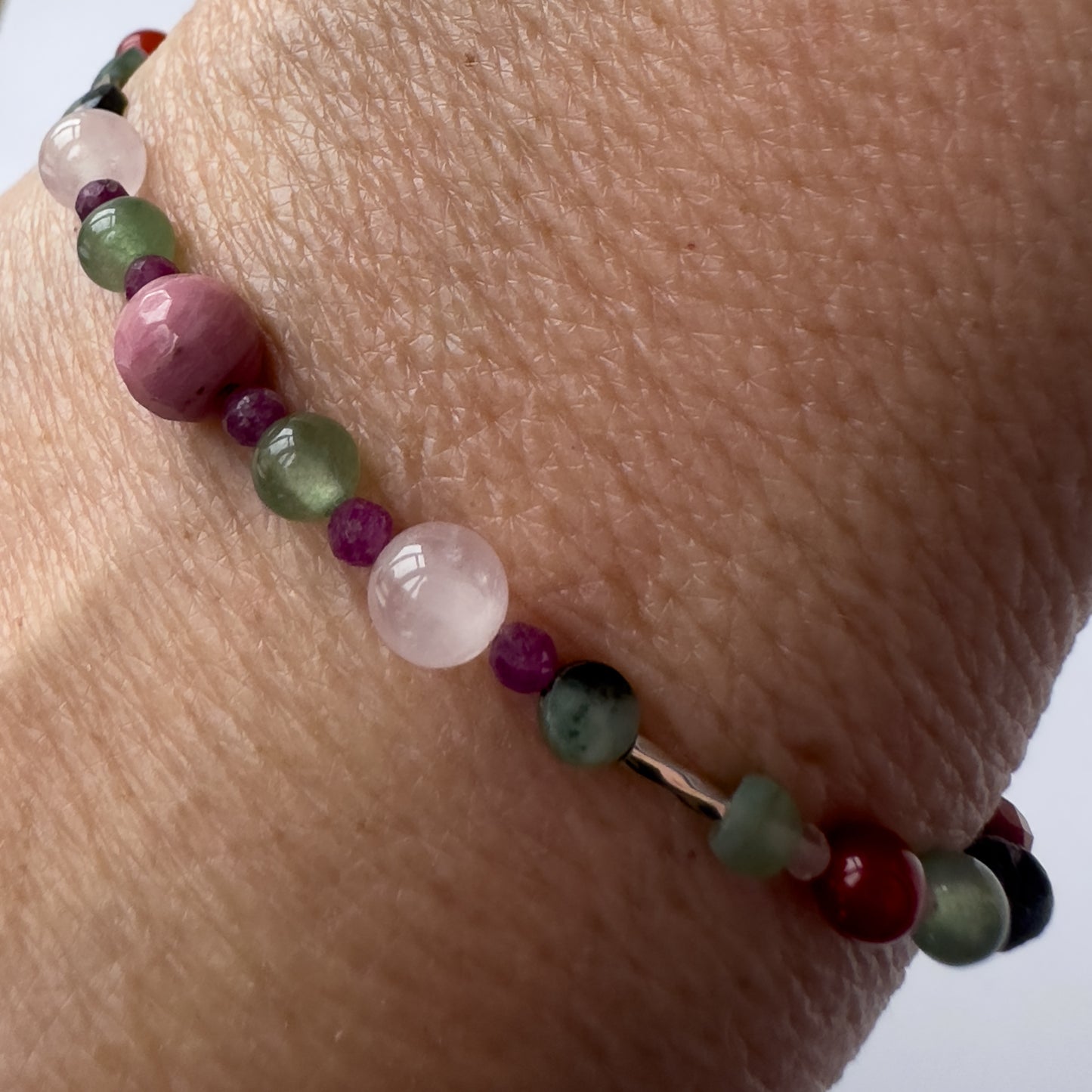 Cancer Healing Crystal bracelet for Grief & Loss on wrist showing Ruby, Rhodonite, Rose Quartz, Chalcedony and Emerald