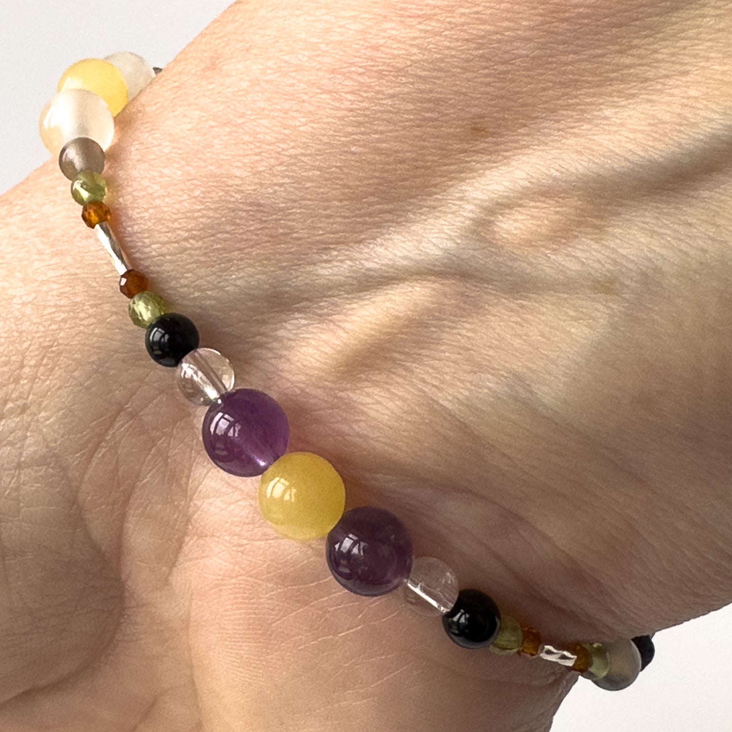 Capricorn Birthstone Healing Crystal bracelet for Determination & Willpower on wrist showing Onyx, Amethyst, Garnet, Peridot, Aragonite and Clear Quartz