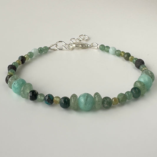 Beaded bracelet with green and black beads on a light gray background