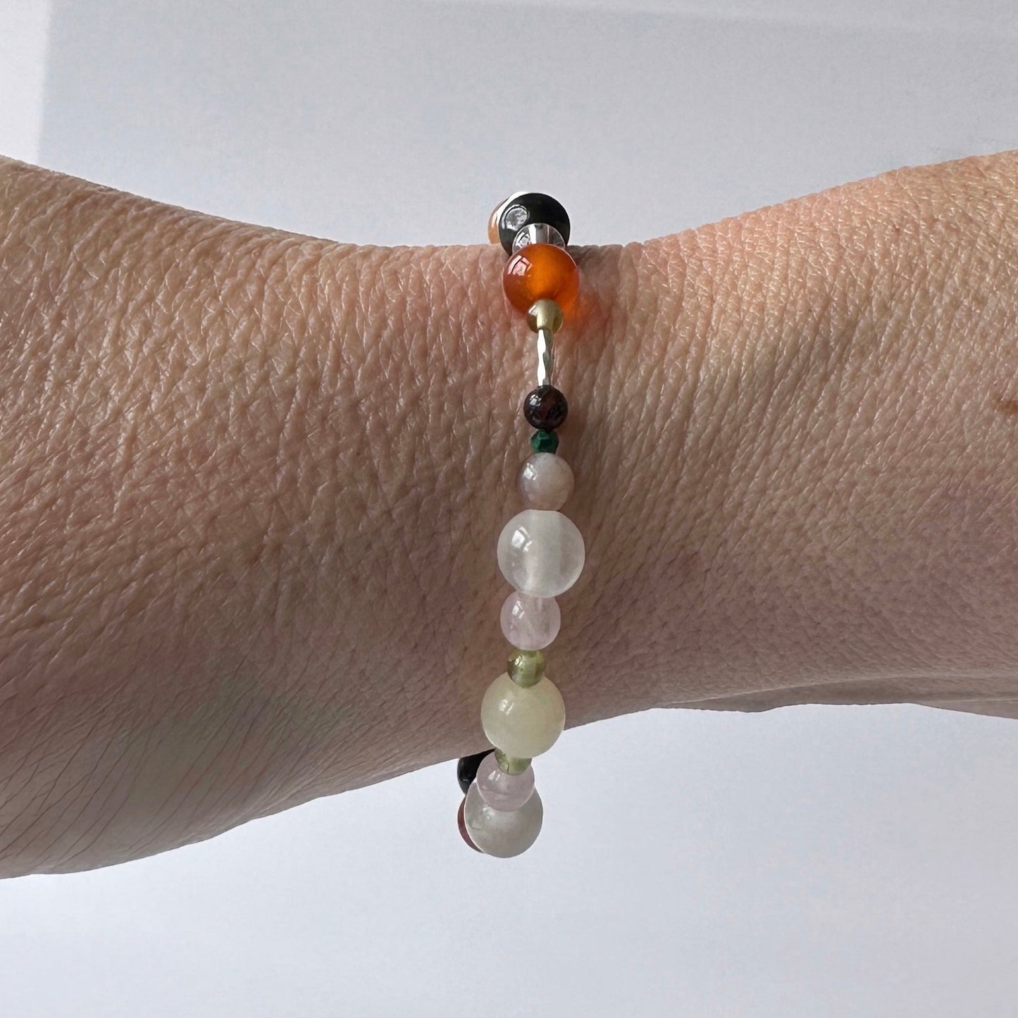 Taurus Handmade Healing Crystal bracelet for Willpower on wrist showing Malachite, Aragonite, Rose Quartz, Carnelian, Red Tiger’s Eye and Selenite