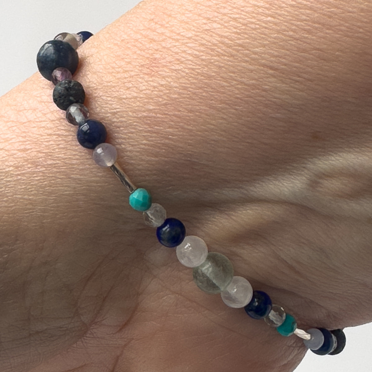 Capricorn Healing Crystal bracelet for Anxiety on wrist showing Turquoise, Blue Lace Agate, Lapis Lazuli, Fluorite, Azurite, Sodalite, Selenite and Lava Stone