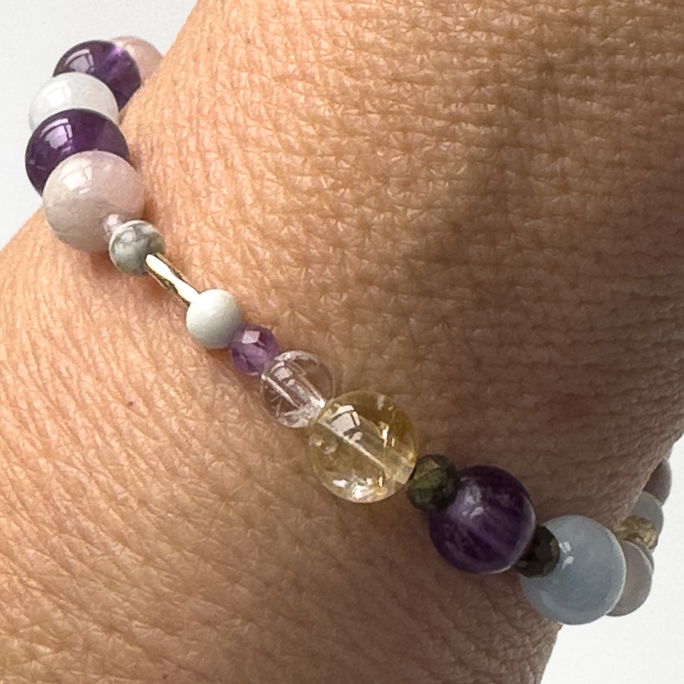 Close-up of Healing crystal bracelet showing Aquamarine, Iron Pyrite, Amethyst, Howlite, Kunzite, Citrine and Clear Quartz on a wrist