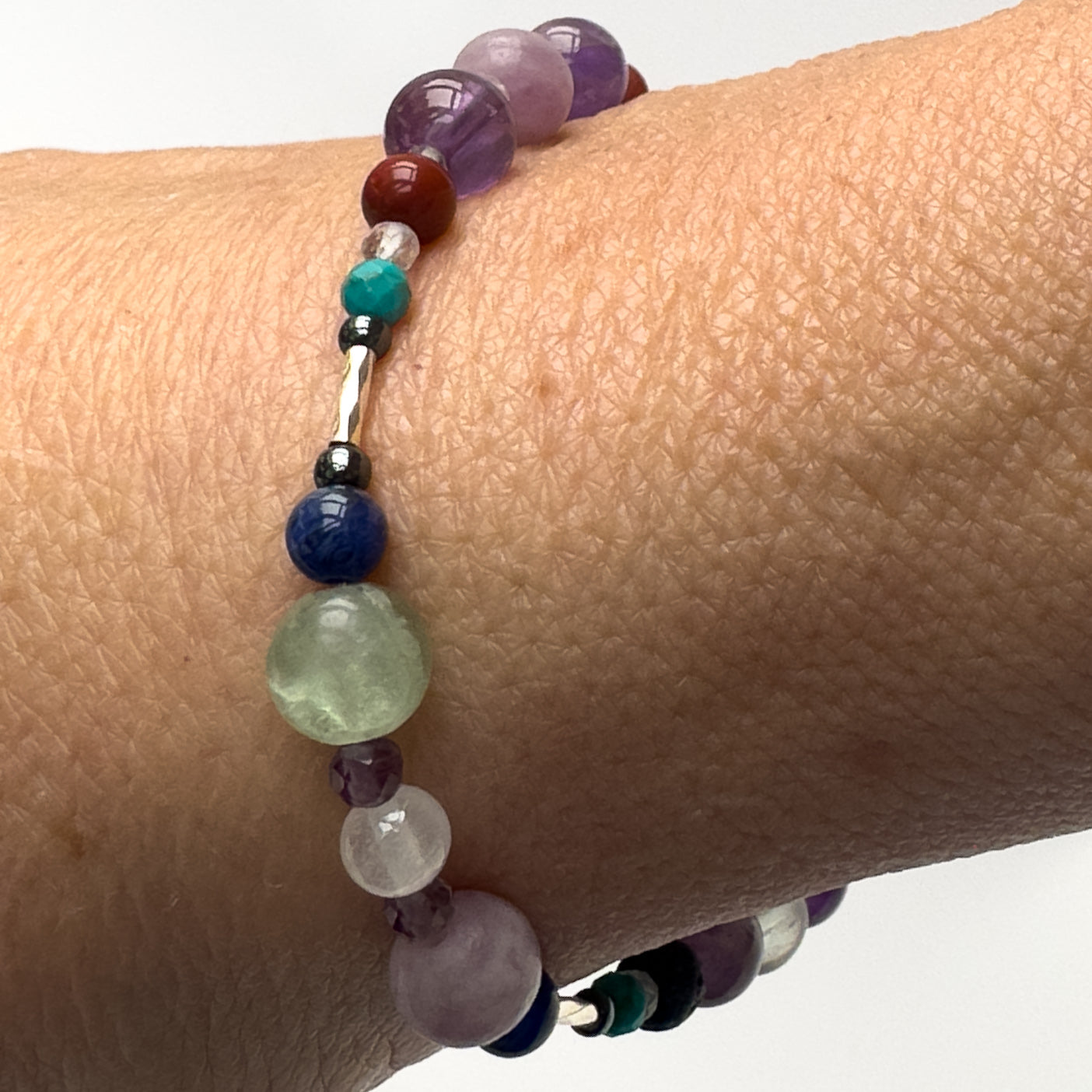 Pisces Healing Crystal bracelet for Willpower on wrist showing Amethyst, Lepidolite, Hematite, Turquoise, Red Jasper, Rainbow Fluorite, Sodalite and Selenite