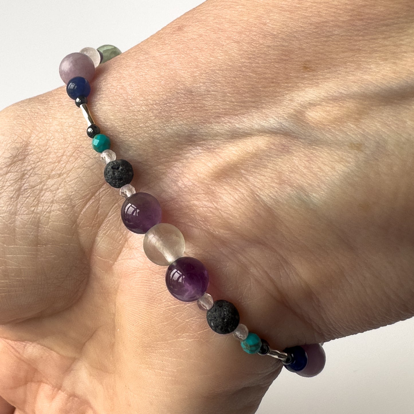 Pisces Healing Crystal bracelet for Willpower on wrist showing Amethyst, Fluorite, Lava Stone, Turquoise and Hematite