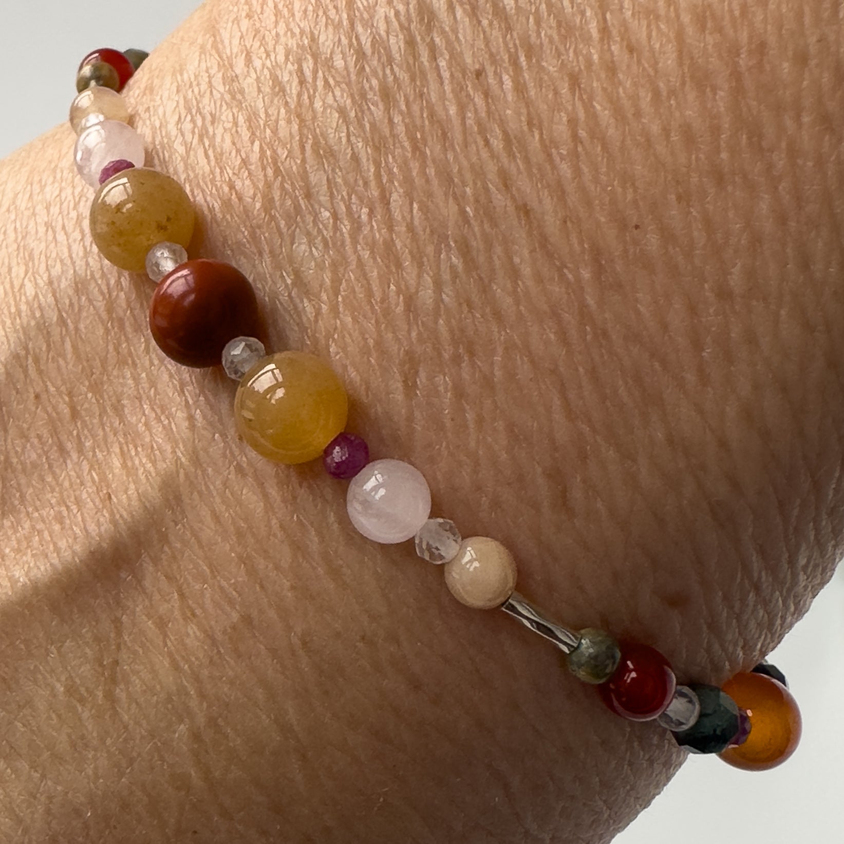 Cancer Healing Crystal bracelet for Willpower on wrist showing Red Jasper, Ruby, Carnelian, Rose Quartz, Sunstone and Clear Quartz