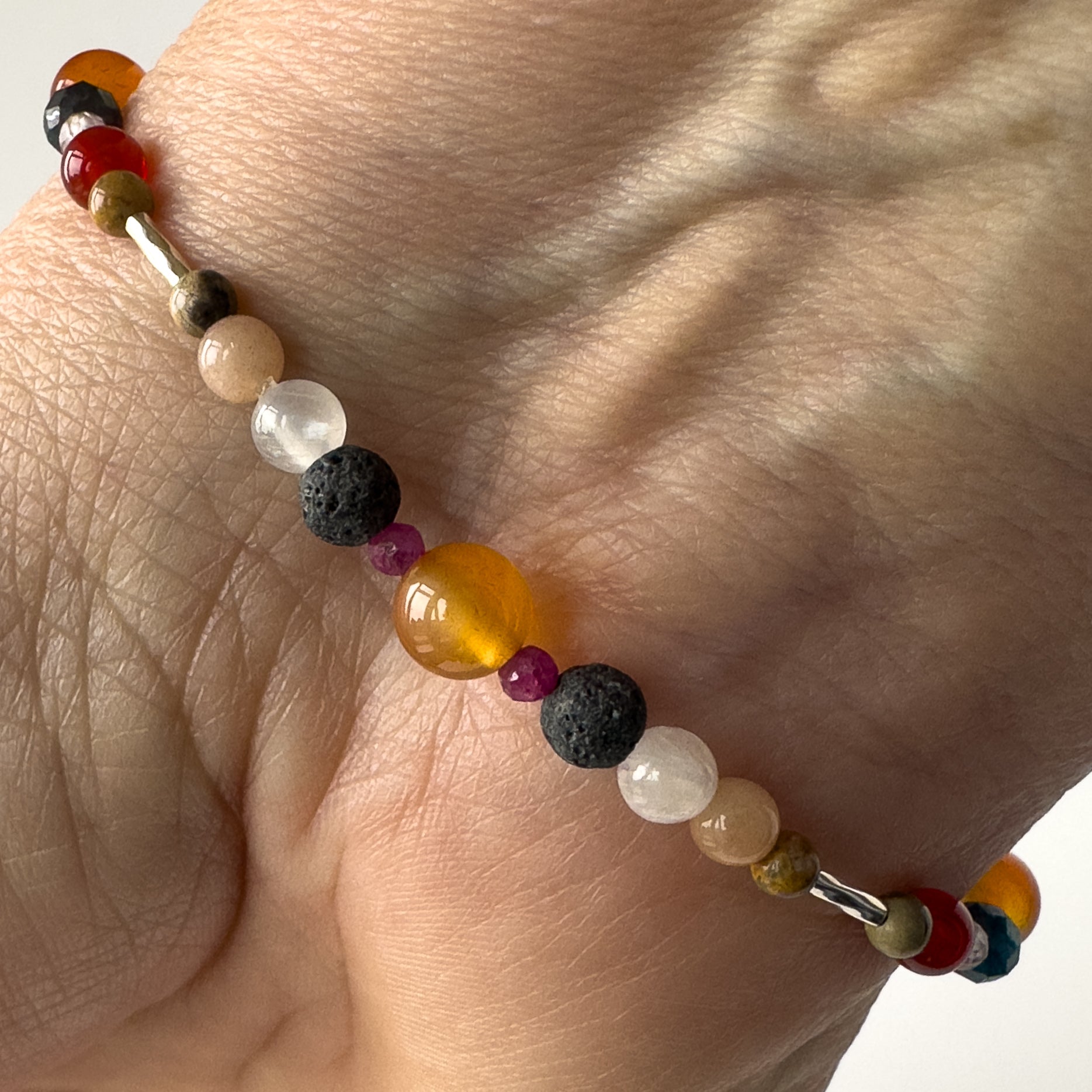 Cancer Healing Crystal bracelet for Willpower on wrist showing Ruby, Carnelian, Leopardskin Jasper, Sunstone, Selenite and Lava Stone