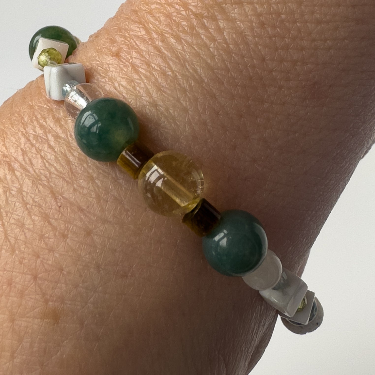 Gemini Healing Crystal bracelet for Love on wrist showing Citrine, Peridot, Moss Agate, Howlite, Tiger’s Eye and Clear Quartz