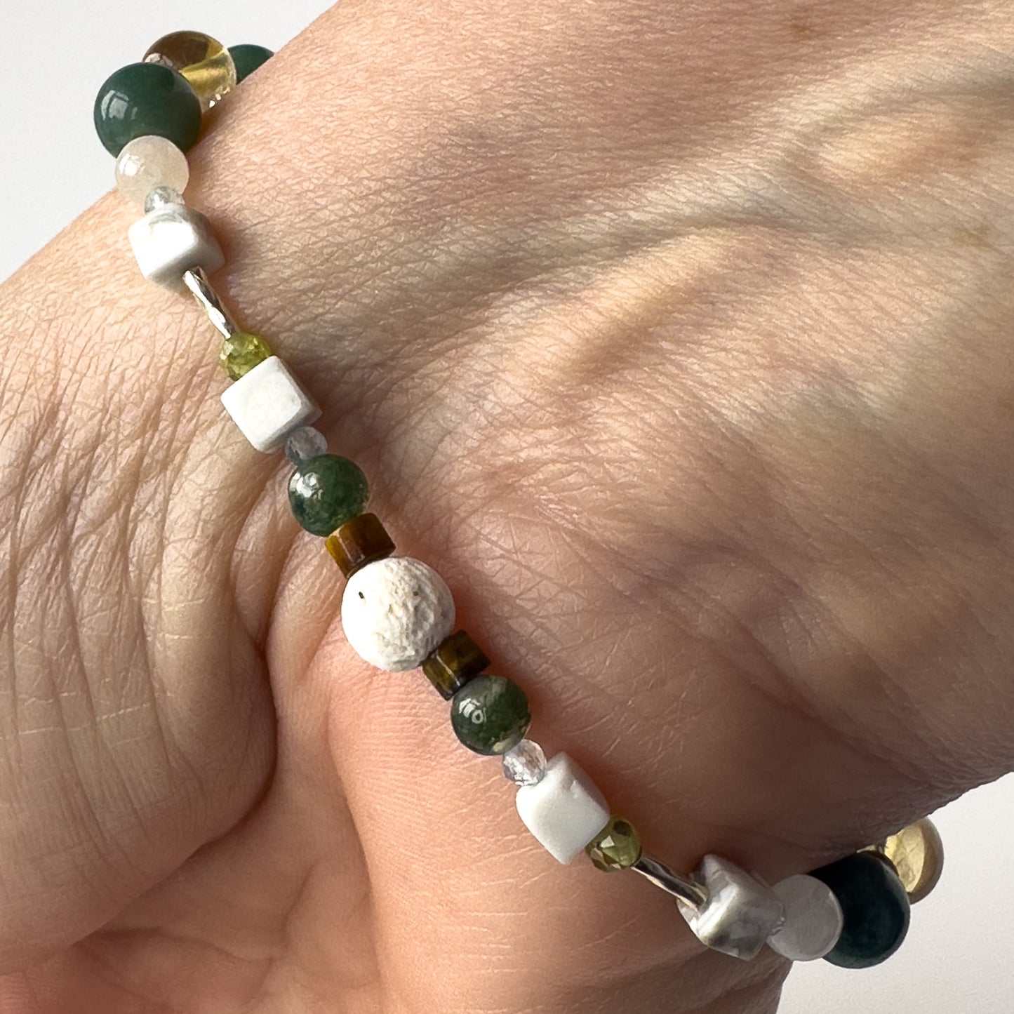 Gemini Healing Crystal bracelet for Love on wrist showing Peridot, Moss Agate, Howlite, Tiger’s Eye, Topaz and Lava Stone