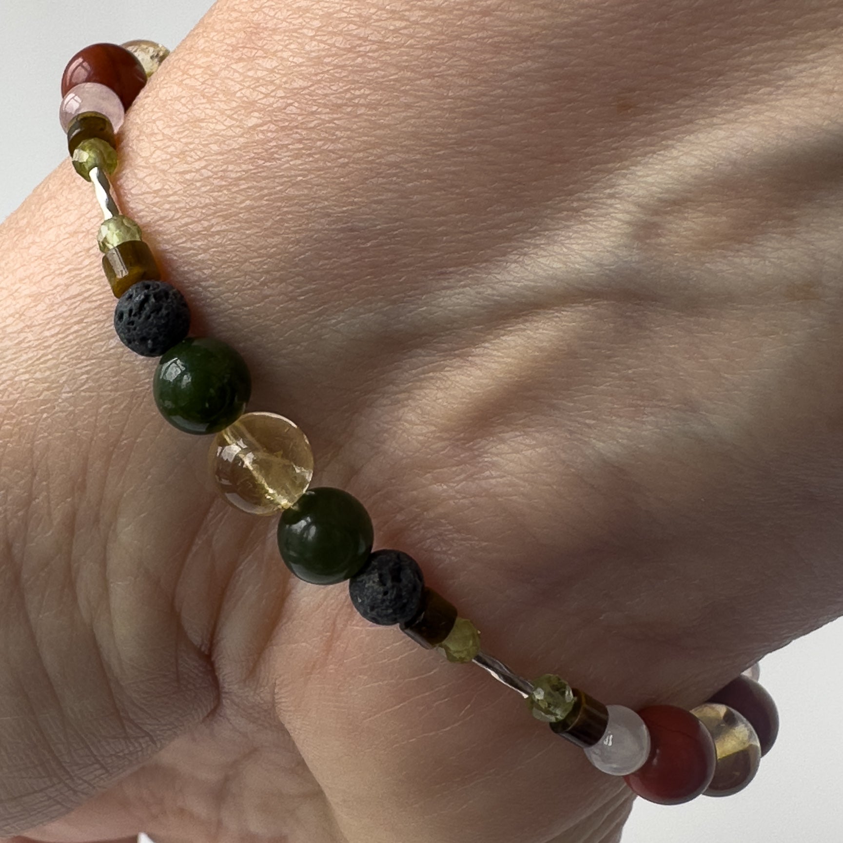 Pisces Healing Crystal bracelet for Love on wrist showing Citrine, Peridot, Jade, Tiger’s Eye and  Lava Stone