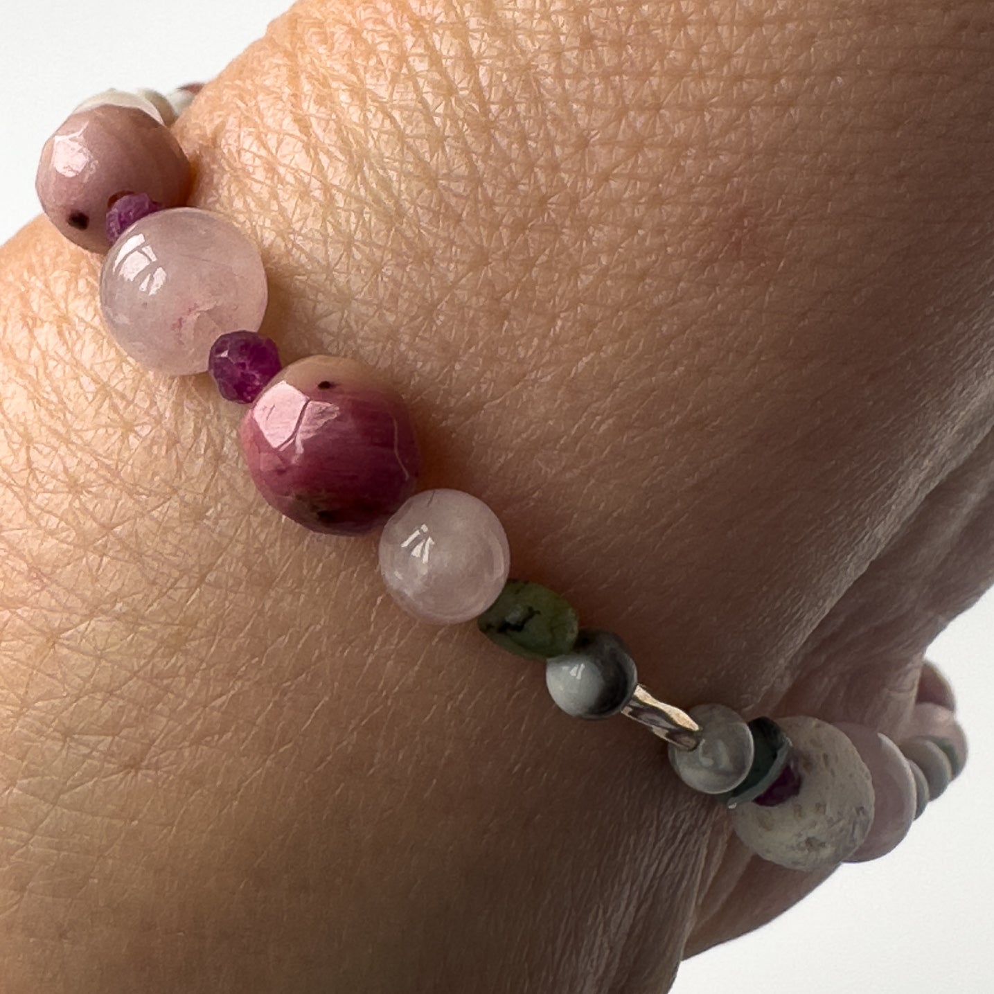 Cancer Healing Crystal bracelet for Love on wrist showing Rose Quartz, Emerald, Howlite, Rhodonite and Ruby