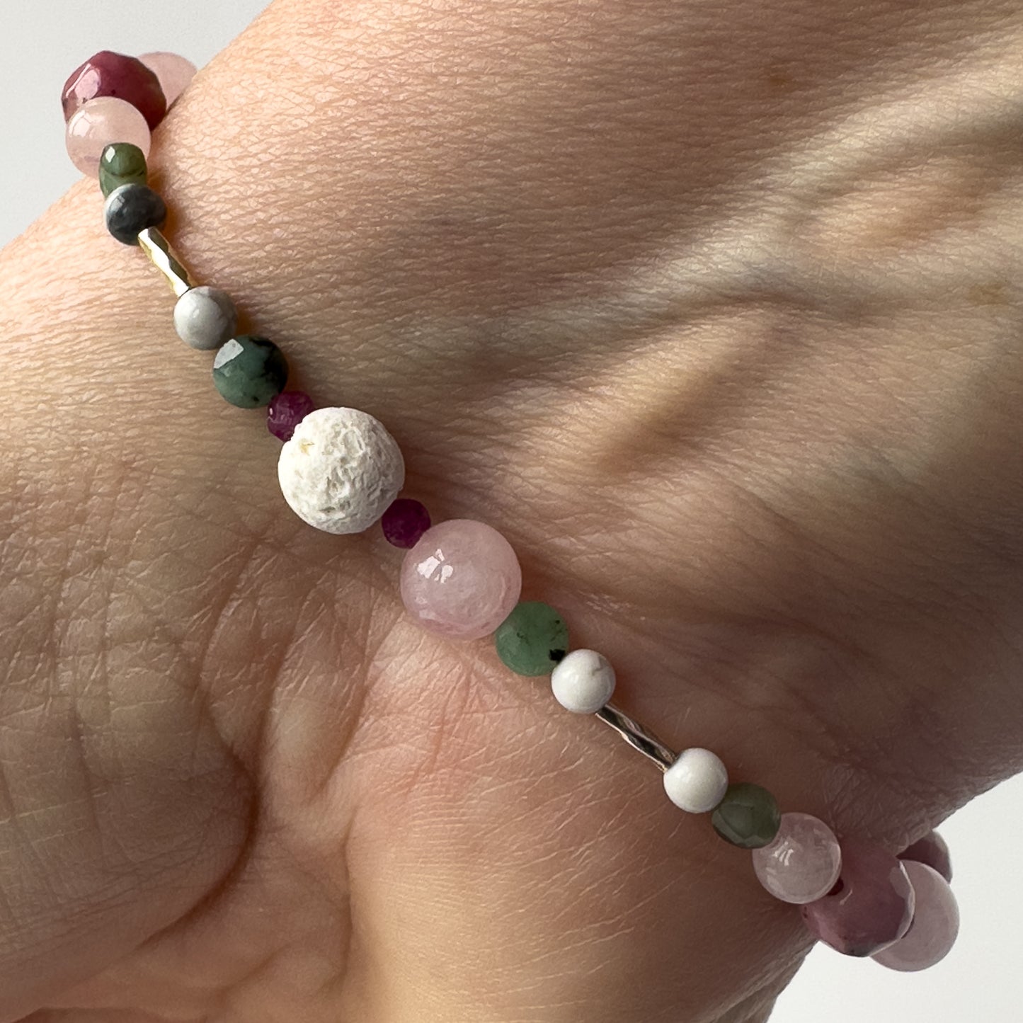 Cancer Healing Crystal bracelet for Love on wrist showing Rose Quartz, Emerald, Howlite, Ruby and Lava Stone