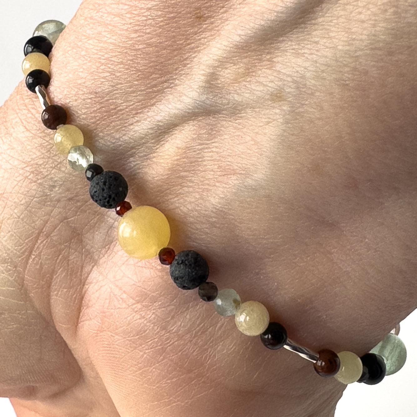 Capricorn Healing Crystal bracelet for Confidence on wrist showing Garnet, Mahogany Obsidian, Onyx, Fluorite and Aragonite